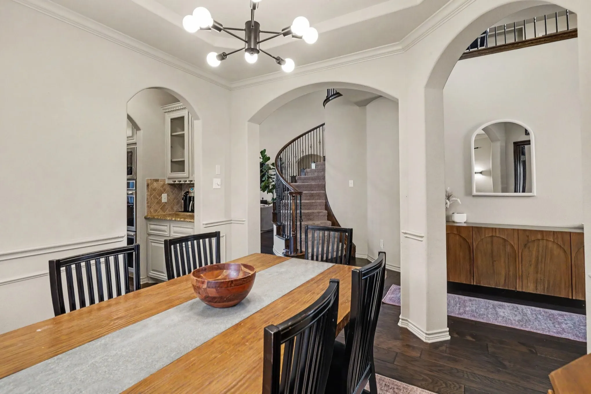 Formal dining area featuring dark wood-finish flooring, a modern chandelier, and arched doorways