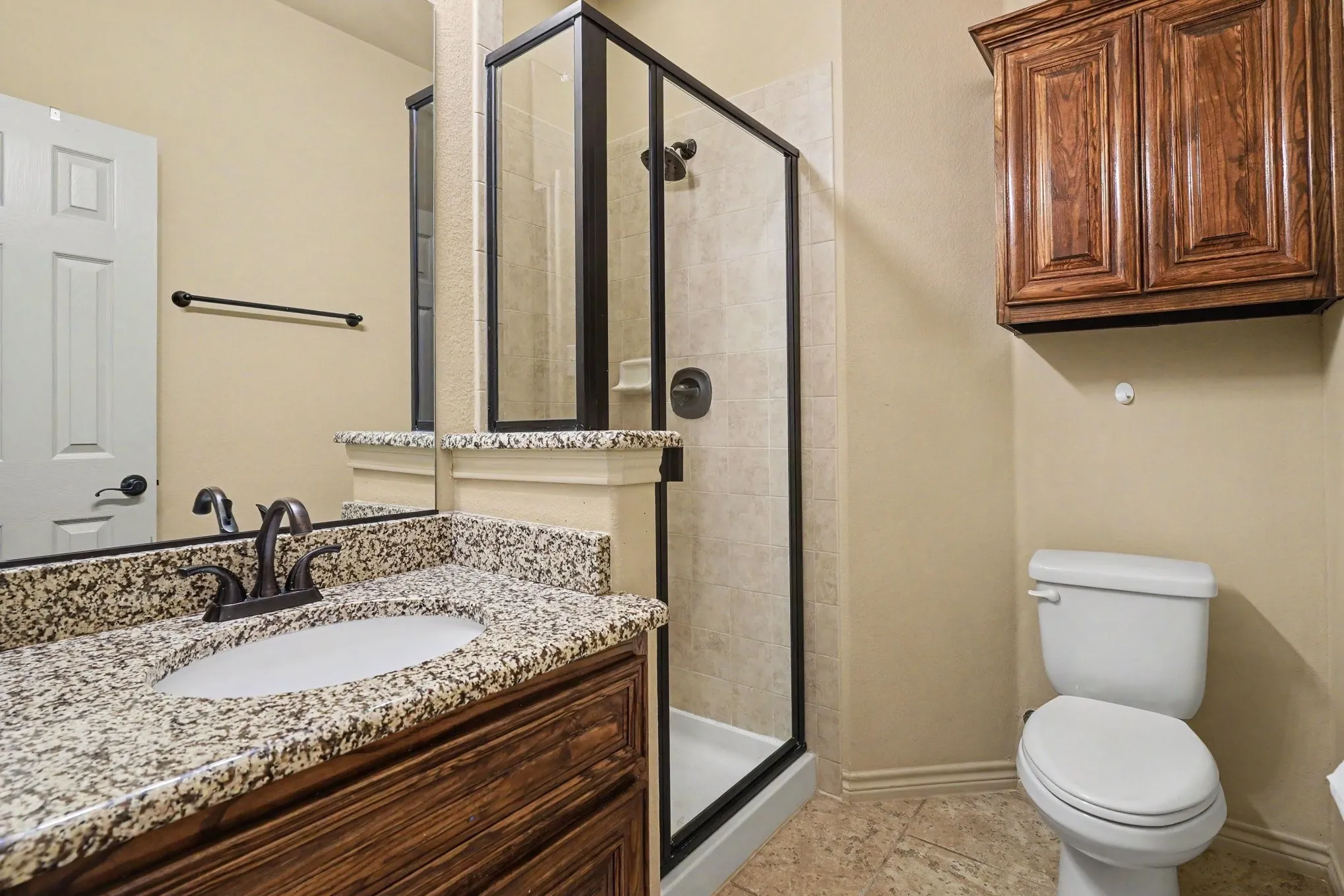 Bathroom featuring a dark wood vanity with a granite countertop, undermount sink, and dark bronze faucet
