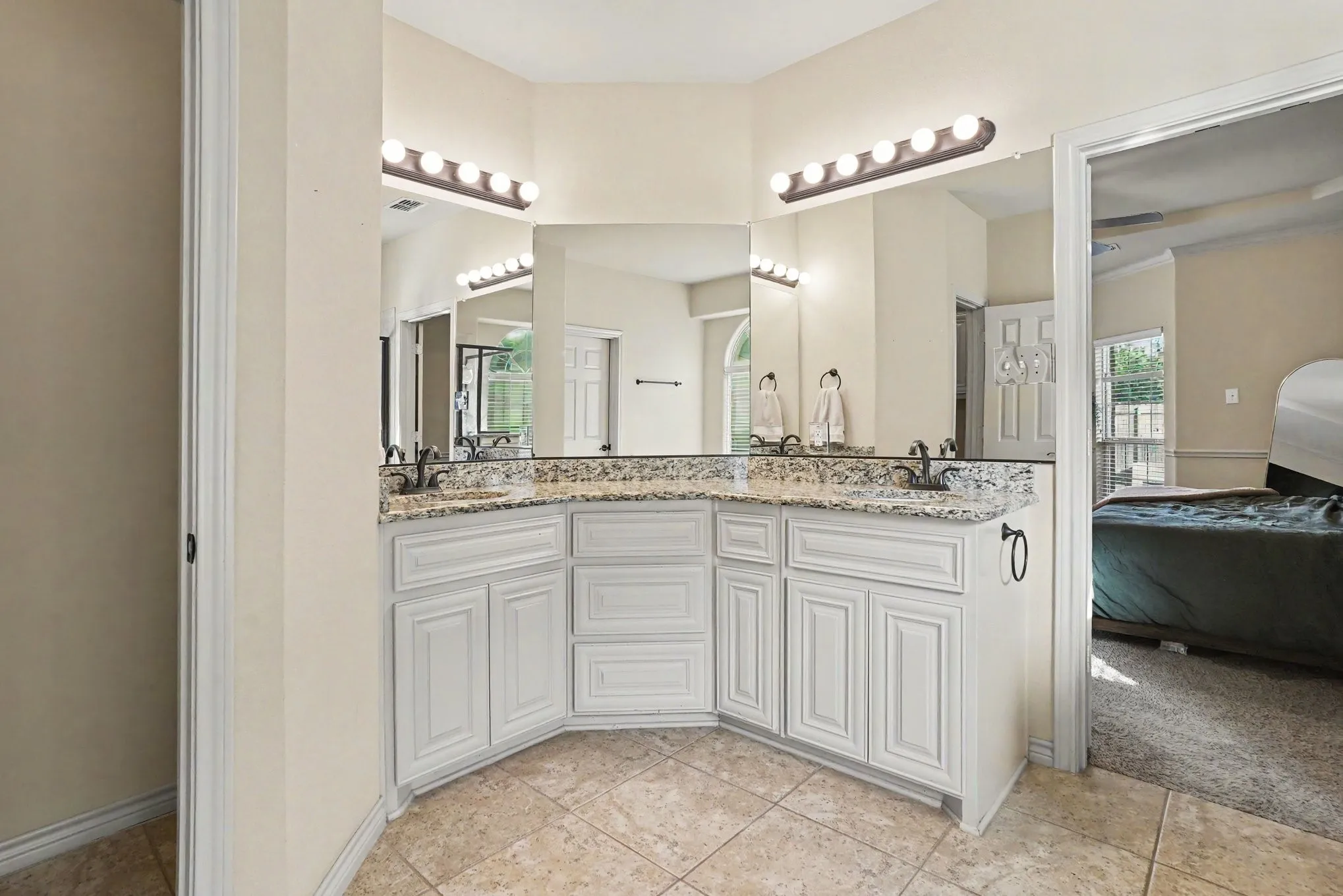 Bathroom featuring a dual vanity with light-toned granite countertops, white cabinetry, and a tile floor
