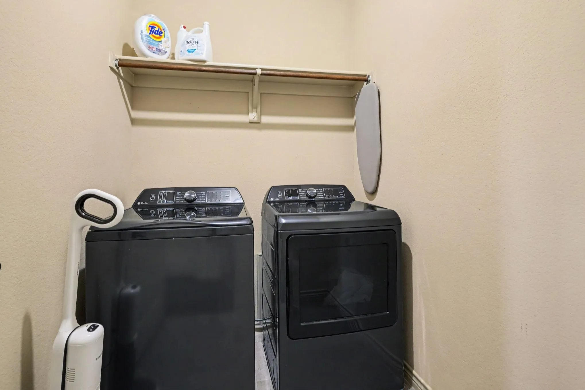 Dedicated laundry area featuring a built-in shelf, clothing rod, and neutral wall tones