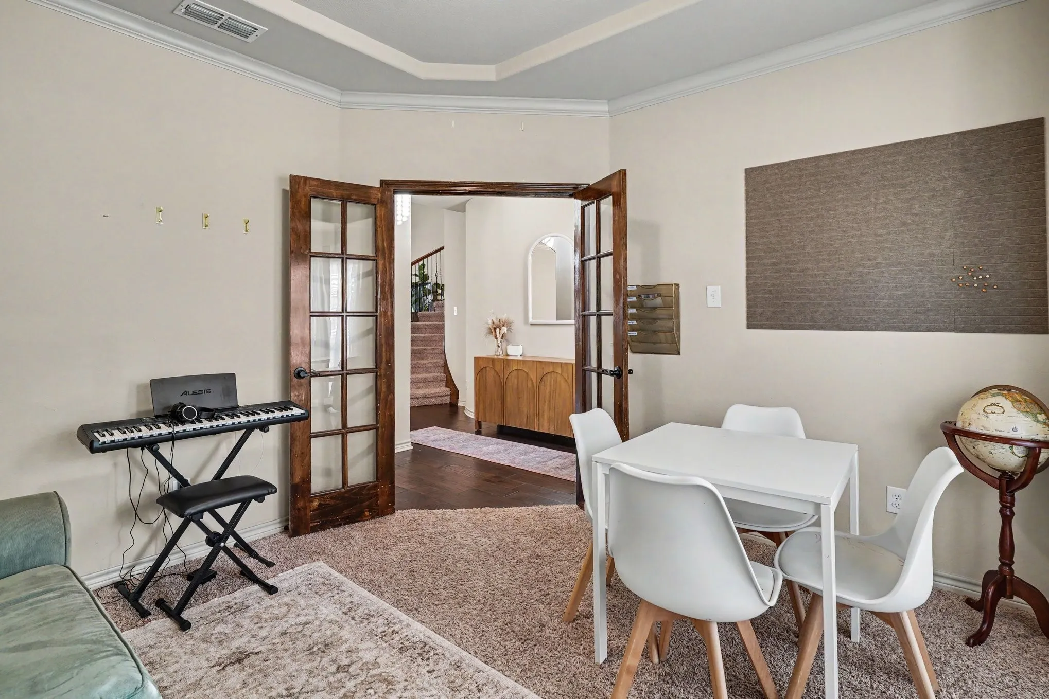 Room featuring French doors with glass panels, tray ceiling, and crown molding