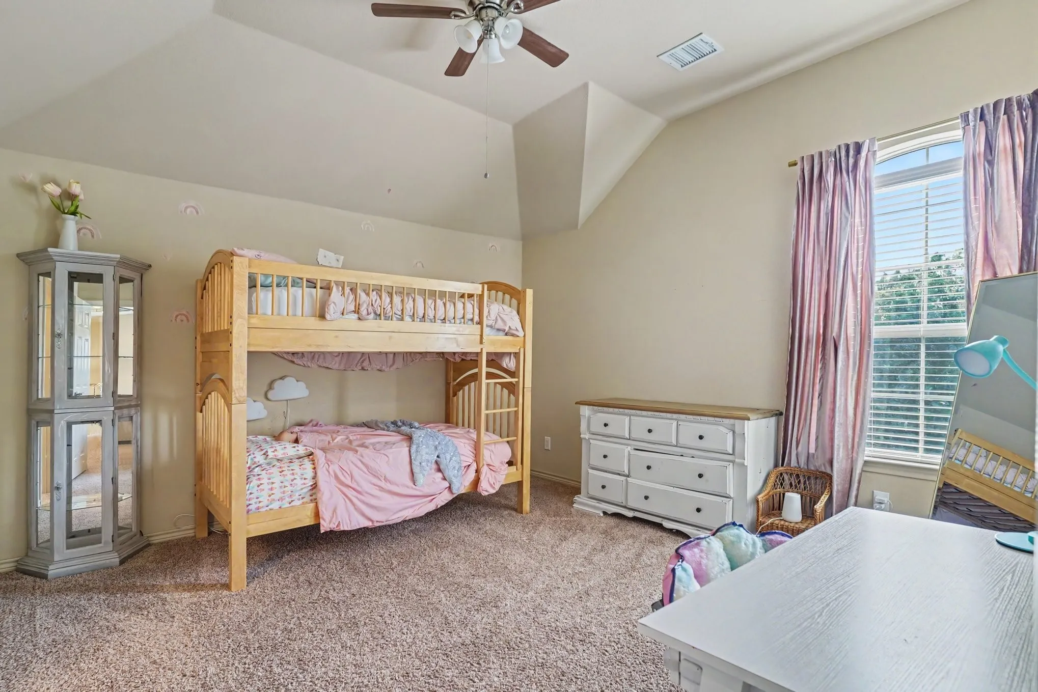 Carpeted room featuring a vaulted ceiling with a ceiling fan, a window with horizontal blinds, and neutral-toned walls