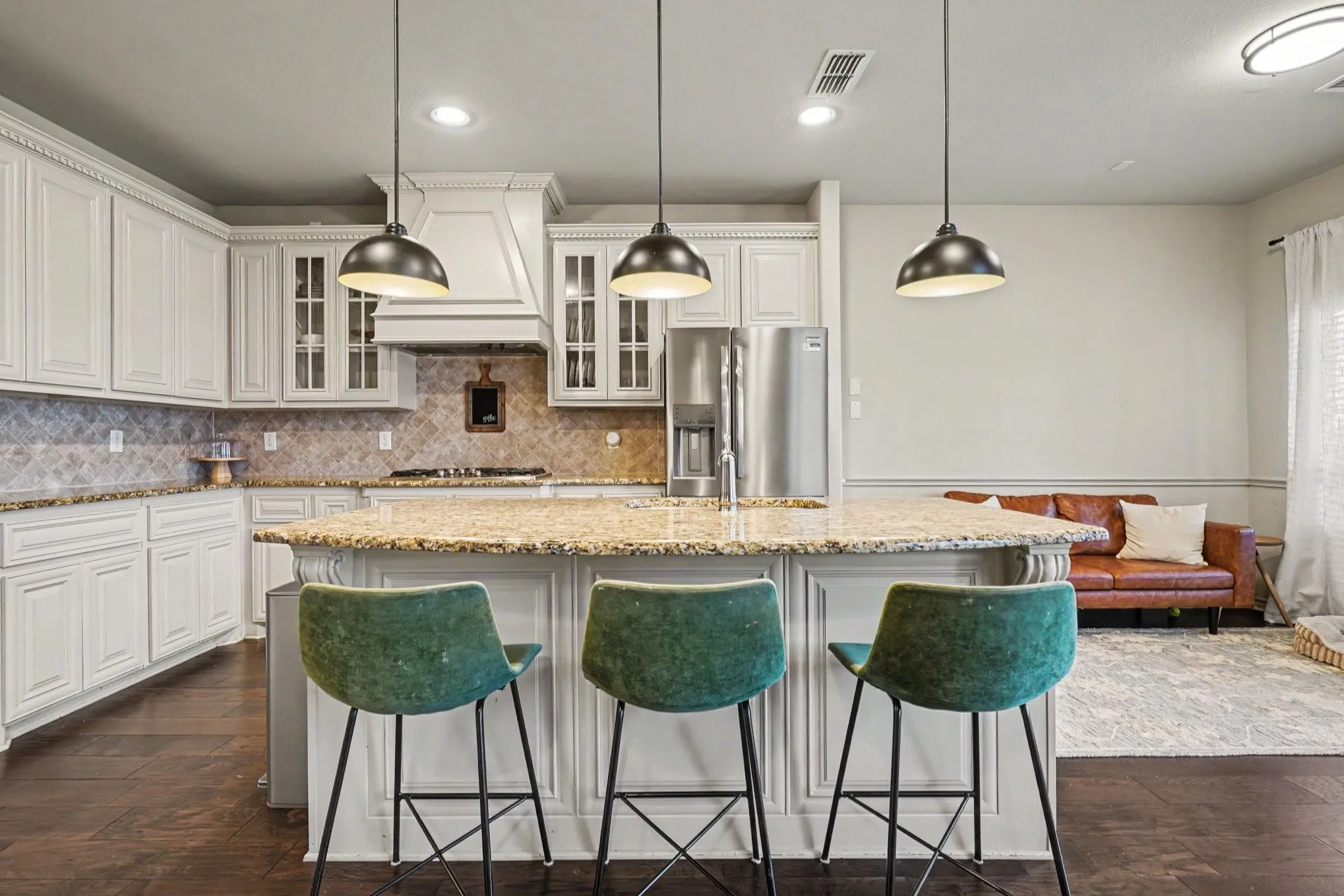 Spacious kitchen featuring an island with a stone countertop, white cabinetry with crown molding, stainless steel appliances, and wood-finish flooring