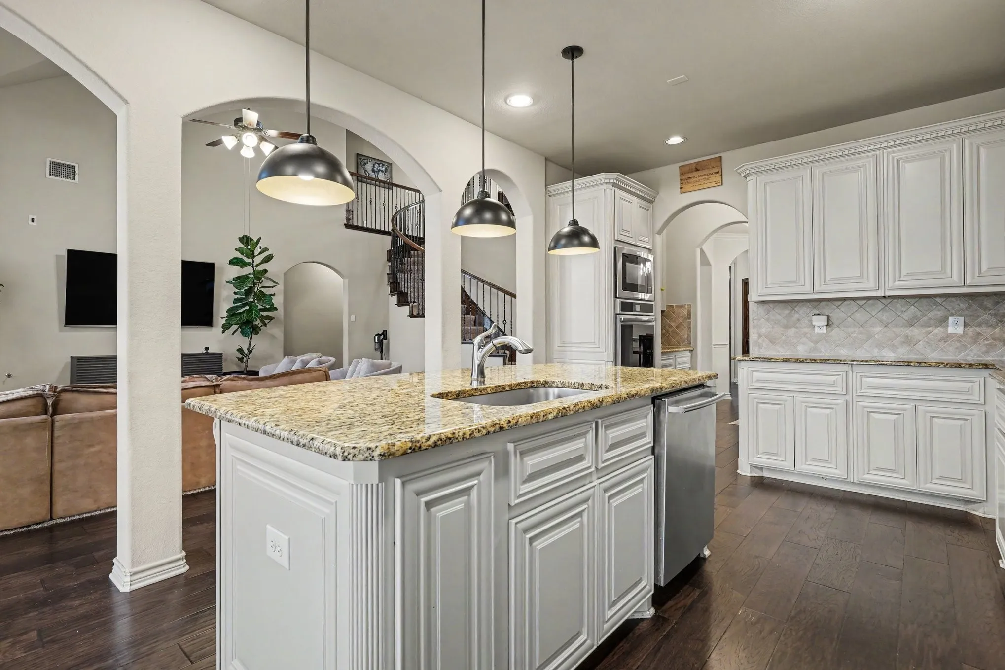 Kitchen island with granite countertop, integrated sink, and pendant lighting