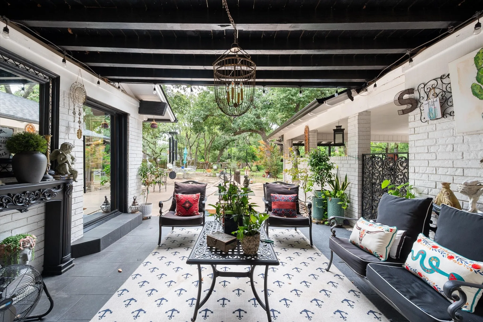 Covered patio featuring a black exposed beam ceiling and white brick exterior