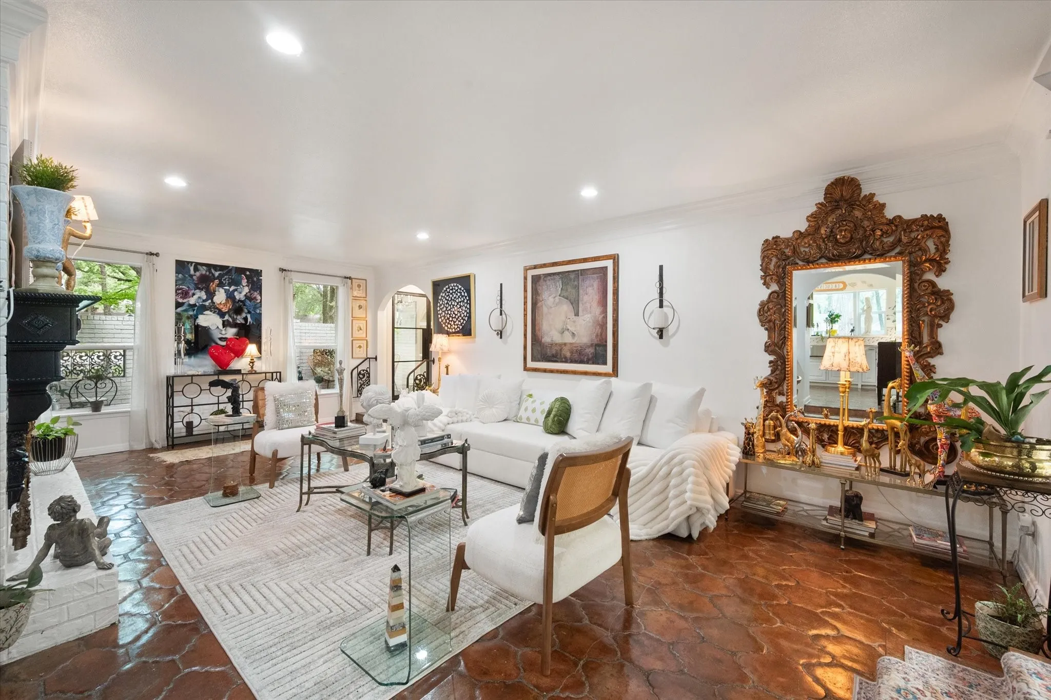 Spacious living area featuring patterned terracotta flooring, recessed lighting, a white painted brick fireplace, and multiple windows providing natural light