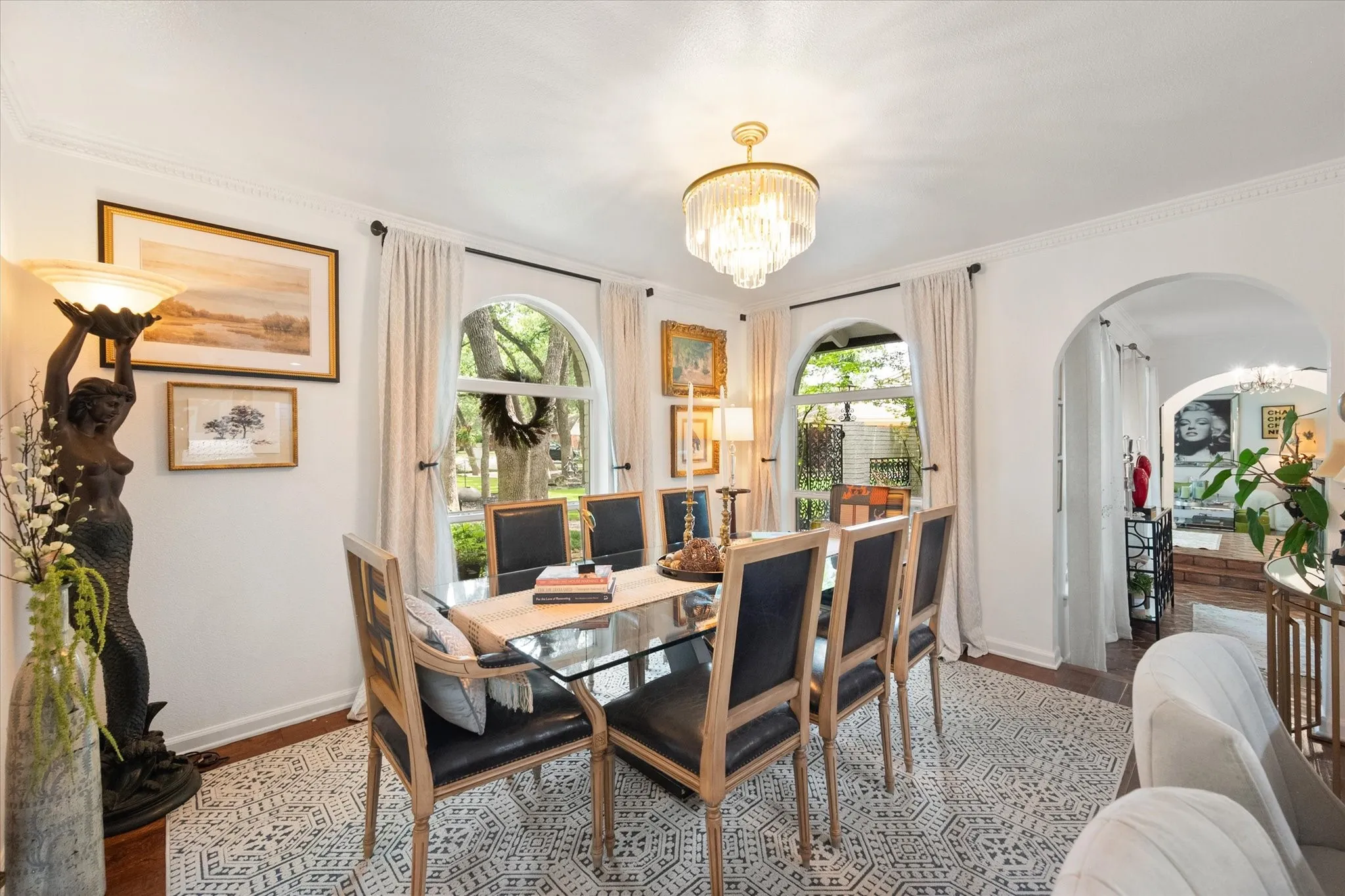 Dining area featuring an arched entry, patterned floor tiles, two arched windows, a chandelier, and crown molding