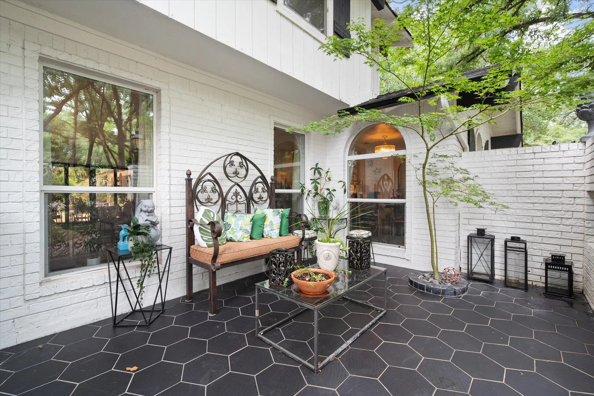 Private outdoor patio featuring hexagonal slate tile flooring, white brick walls, and a prominent arched window