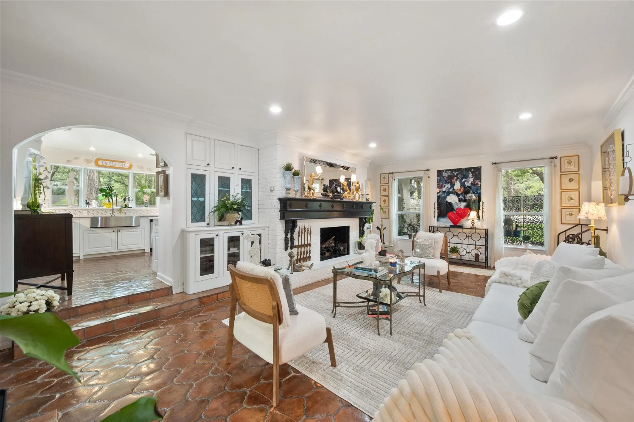 Spacious living area featuring a fireplace with a dark wood mantel, white brick surround, recessed lighting, and white built-in cabinetry