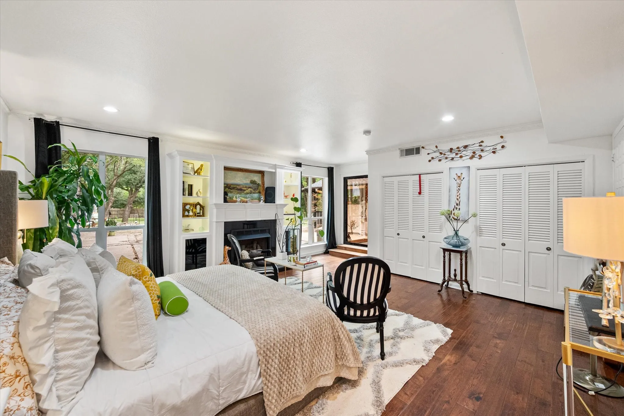 Spacious room featuring wood-finish flooring, a fireplace with a white mantle, and built-in shelving