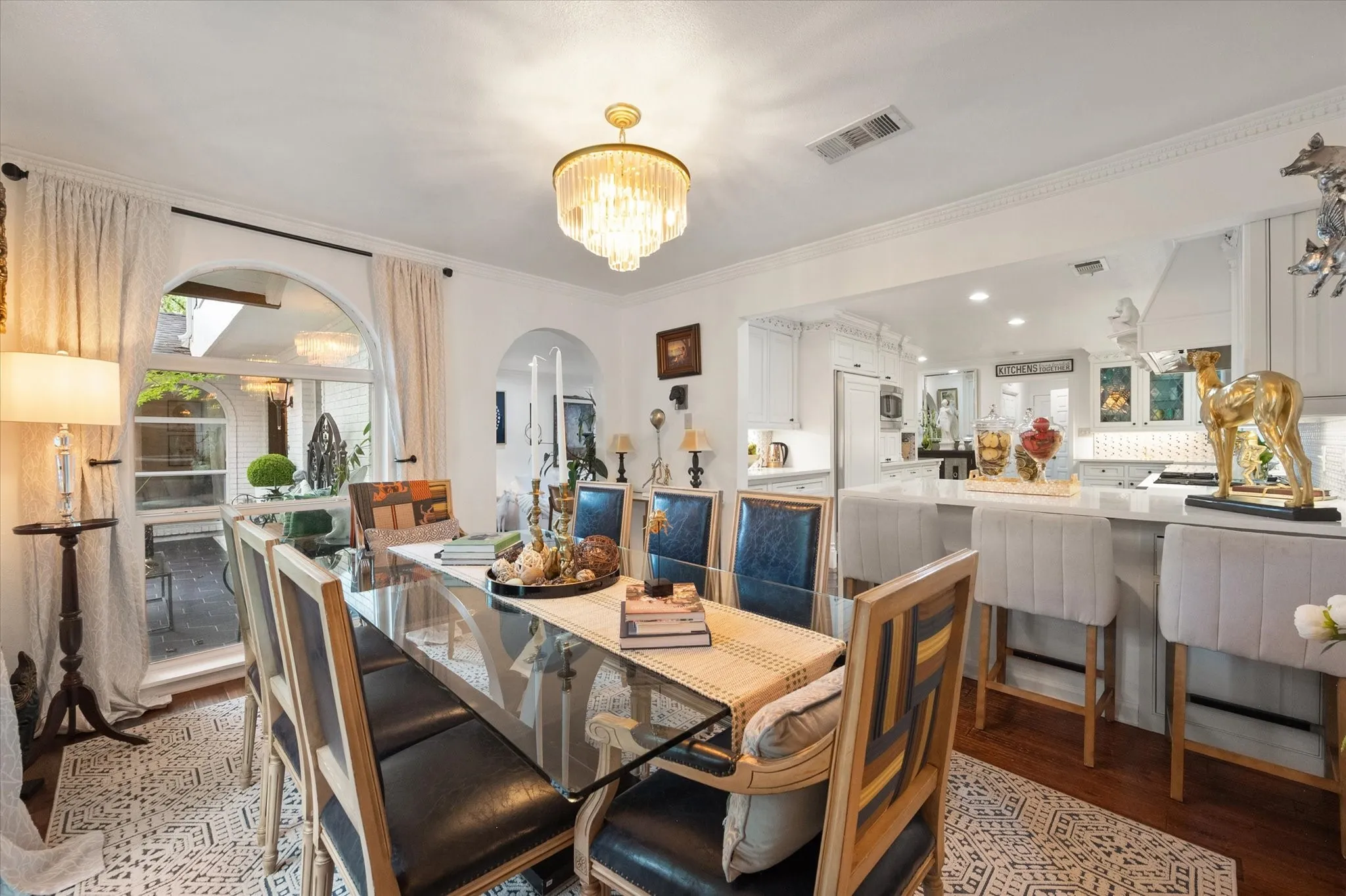 Dining area with a glass-top table, wood-finish flooring, and an ornate chandelier