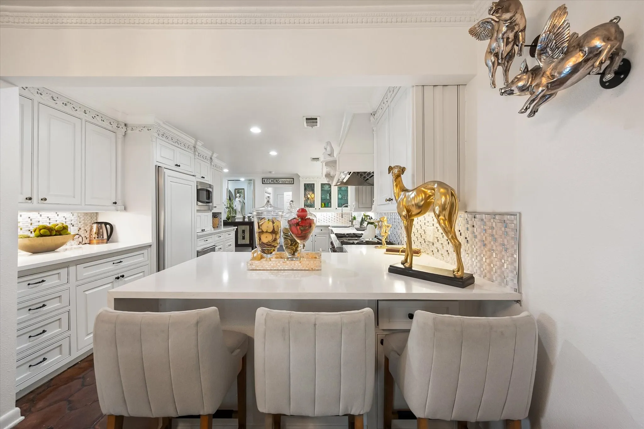 Bright kitchen featuring white cabinetry, a large center island with seating, a stainless steel refrigerator, and recessed lighting