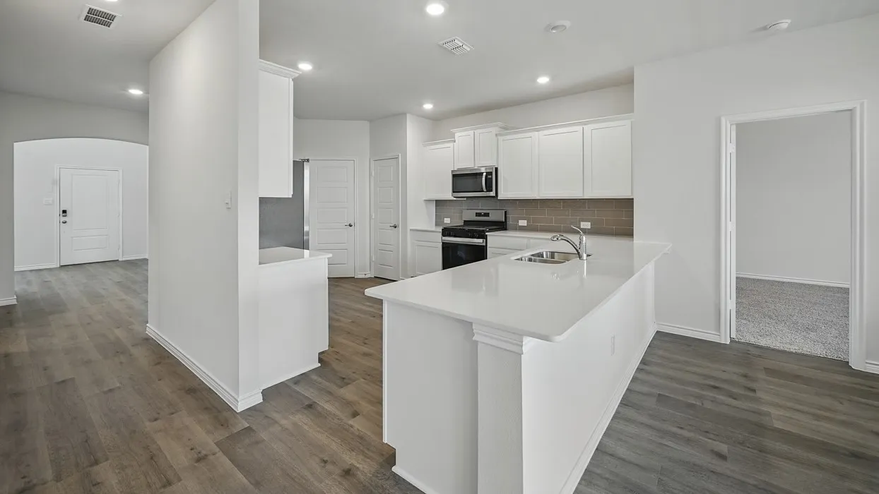 Kitchen featuring a large island with an undermount sink, white shaker cabinetry, stainless steel appliances, and a tiled backsplash