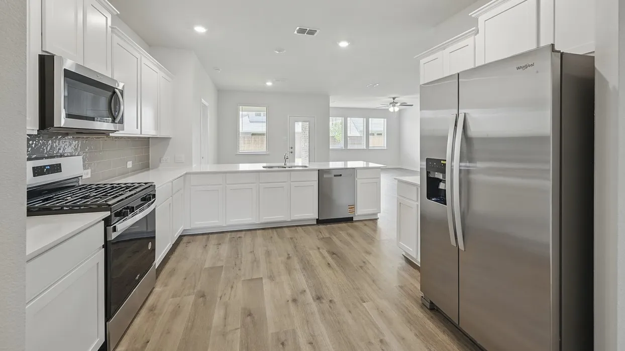 Contemporary kitchen featuring white cabinetry, stainless steel appliances, wood-finish flooring, recessed lighting, and a grey tile backsplash