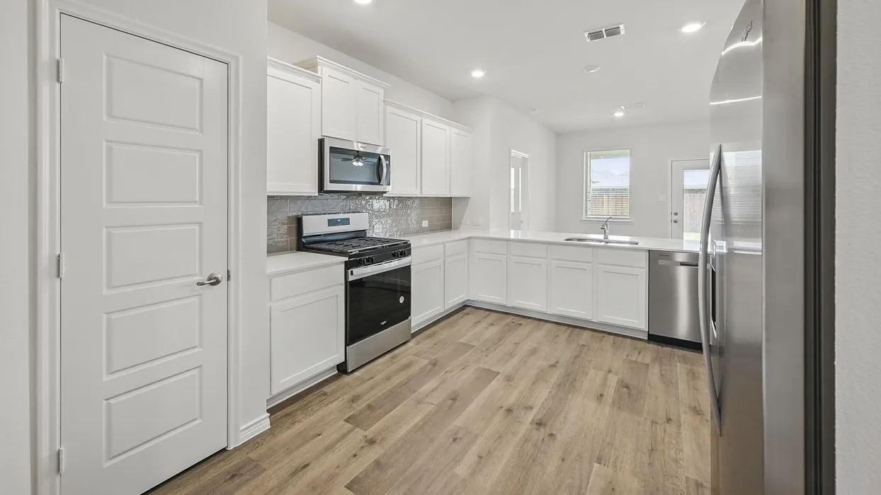 Modern kitchen featuring white cabinetry, stainless steel appliances, wood-finish flooring, and a white countertop