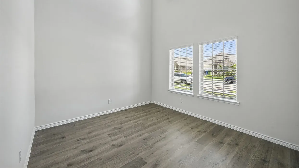 Spacious room featuring vaulted ceilings, wood-finish flooring, white baseboards, and two large windows with blinds