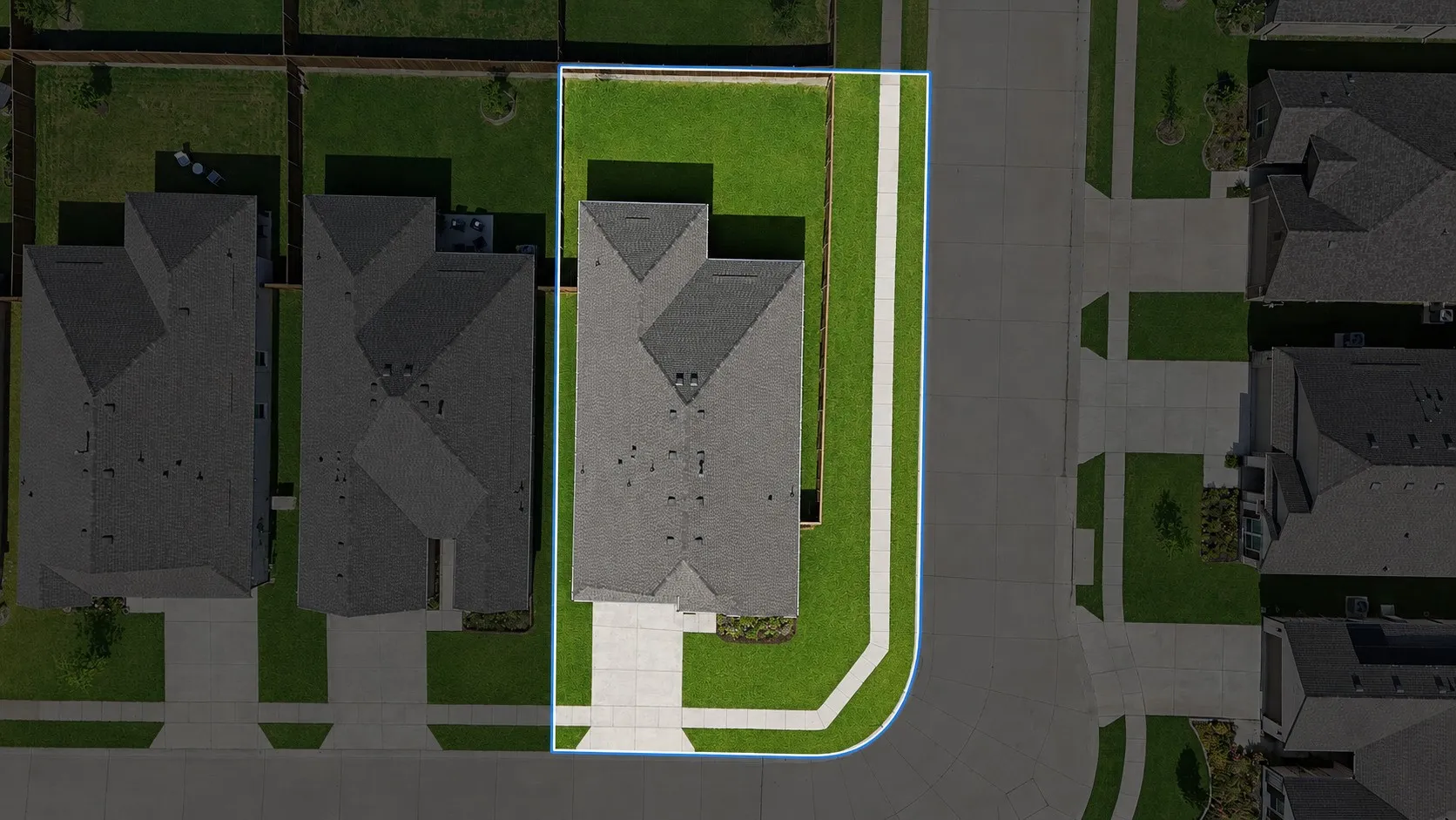 Corner lot property featuring a dark shingle roof and a light concrete driveway