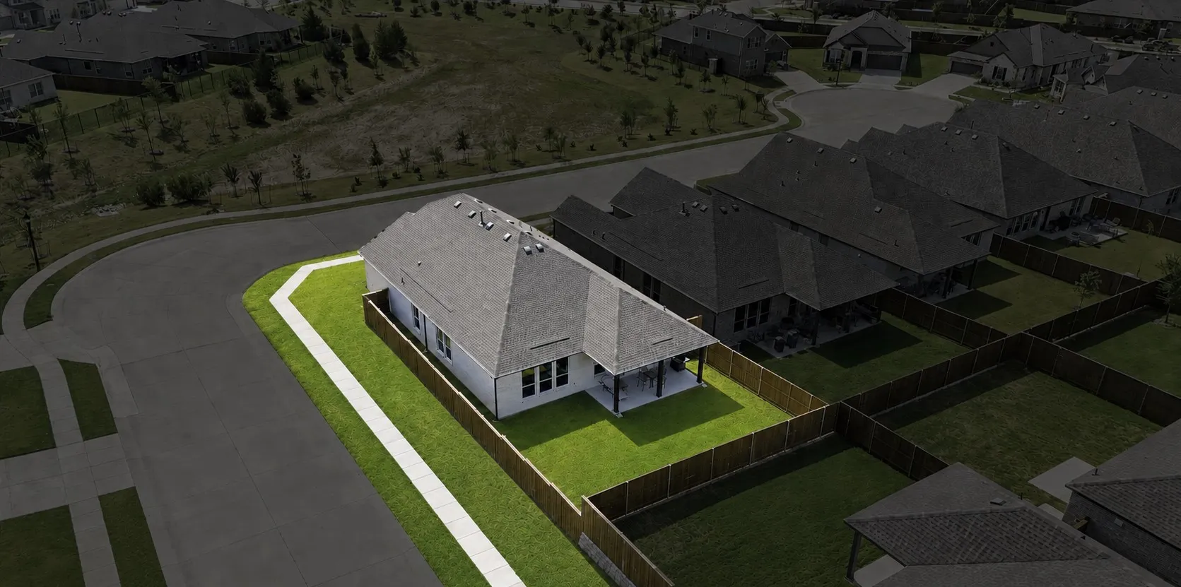 Single-story residence featuring a white exterior, gray shingle roof, covered back patio, and a fenced backyard with green lawn