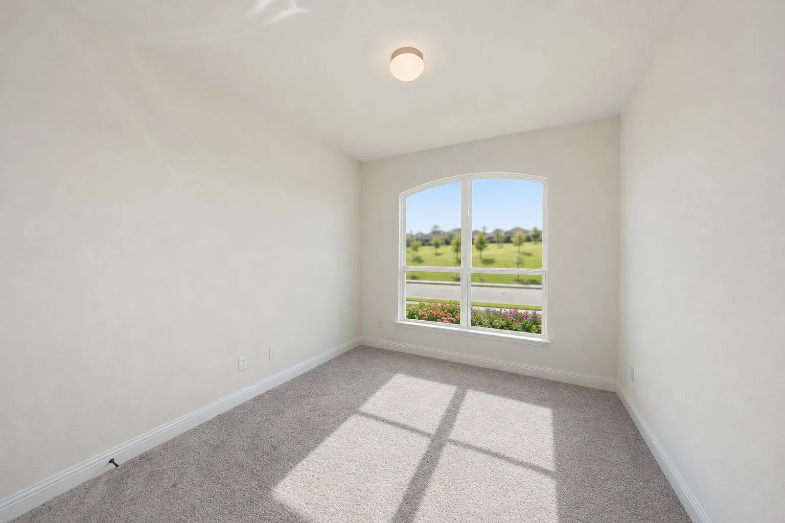 Bedroom 1 featuring an arched window, neutral wall paint, and light-colored carpet flooring