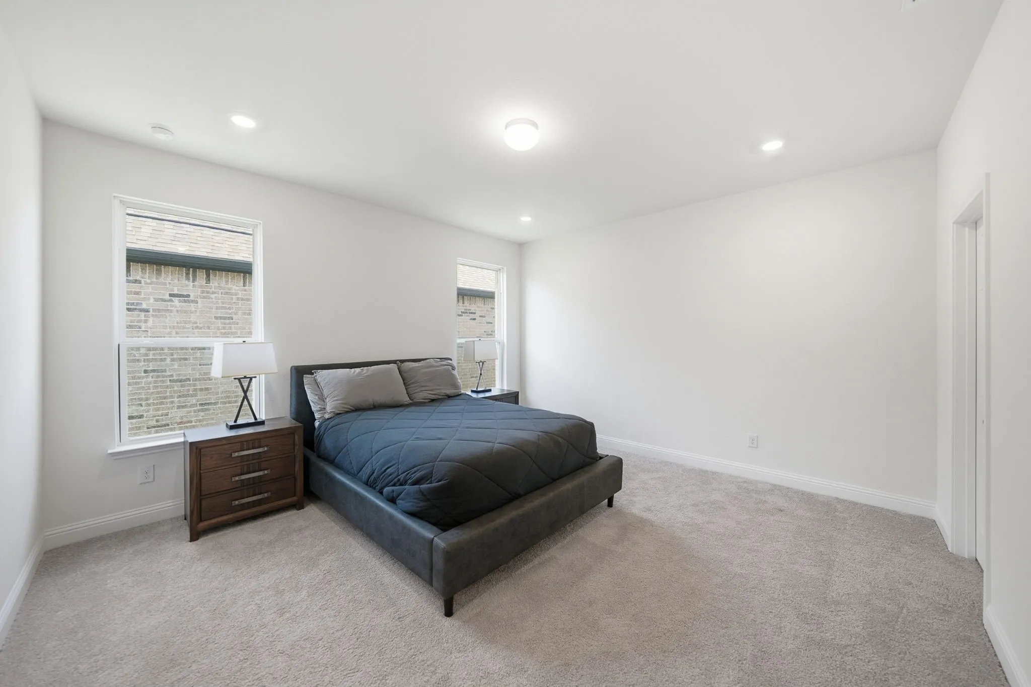 Carpeted room with recessed lighting and two windows