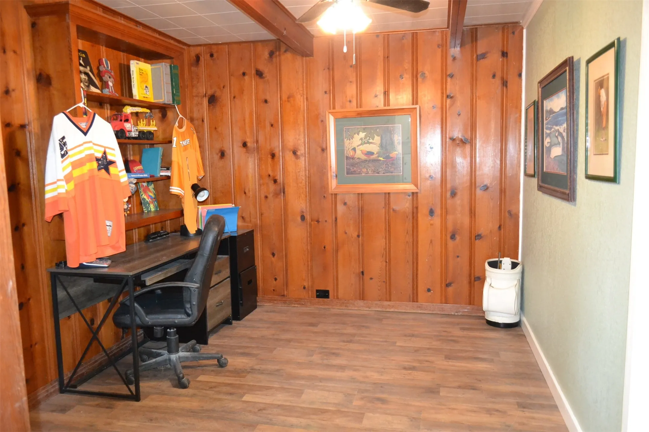 Room featuring wood-paneled walls, wood-finish flooring, and exposed ceiling beams