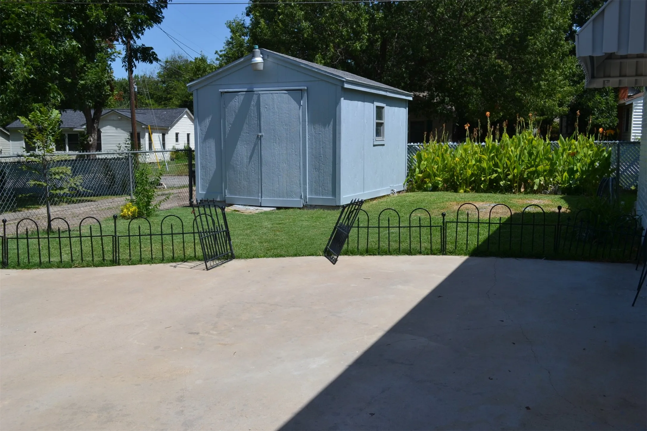 Backyard featuring a concrete patio, a detached storage shed, and a manicured lawn