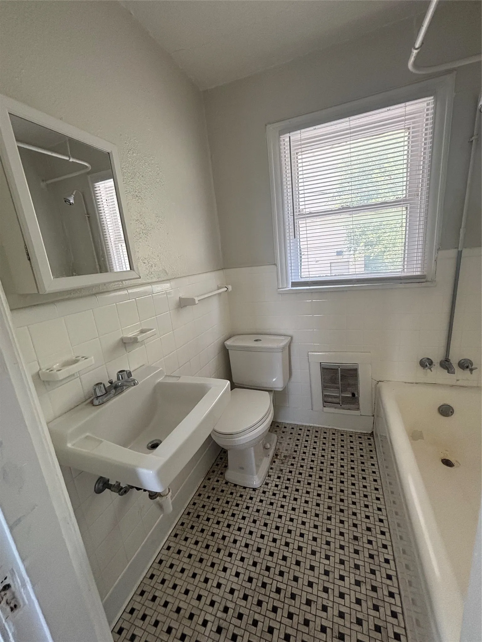 Bathroom featuring white ceramic wall tile, patterned floor tile, a pedestal sink, and a window with blinds
