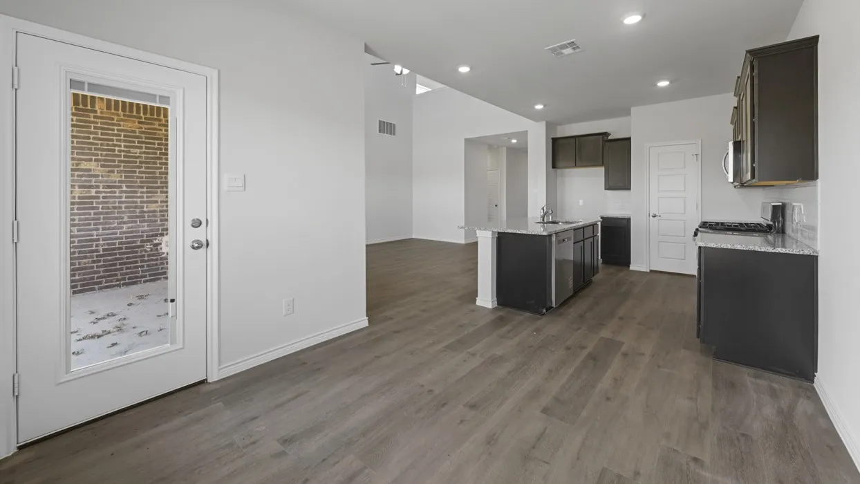 Open-concept kitchen and living area featuring wood-finish flooring, recessed lighting, a kitchen island with sink and integrated dishwasher, dark cabinetry, and white subway tile backsplash