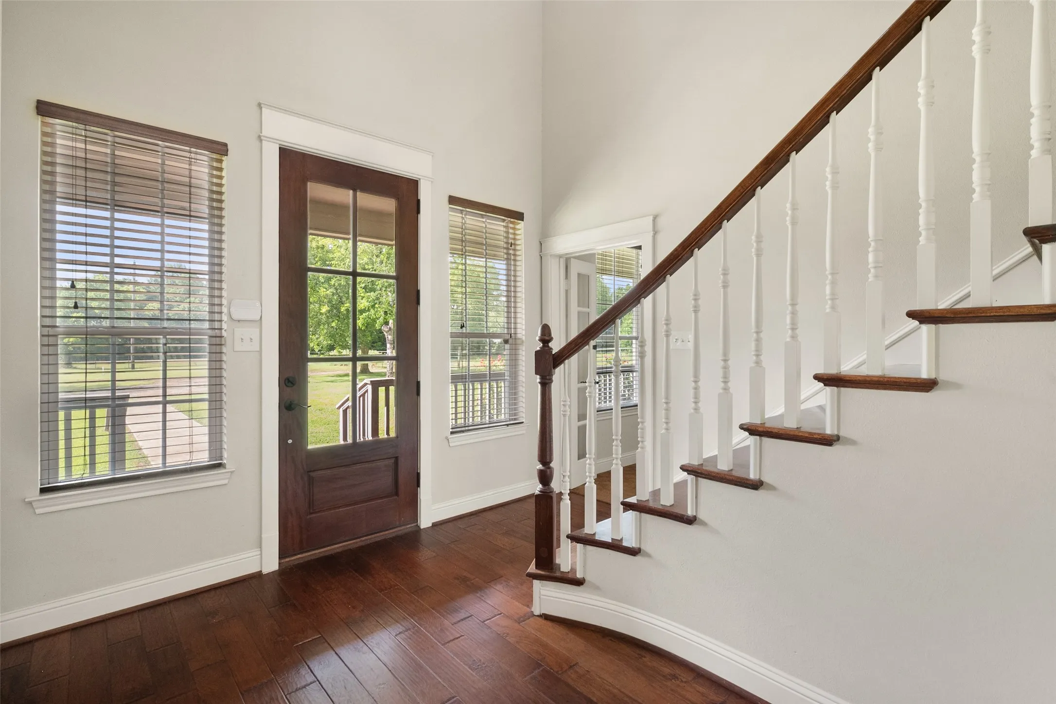Light-filled front entry showcasing hardwood floors, traditional staircase details and beautiful natural woodwork.