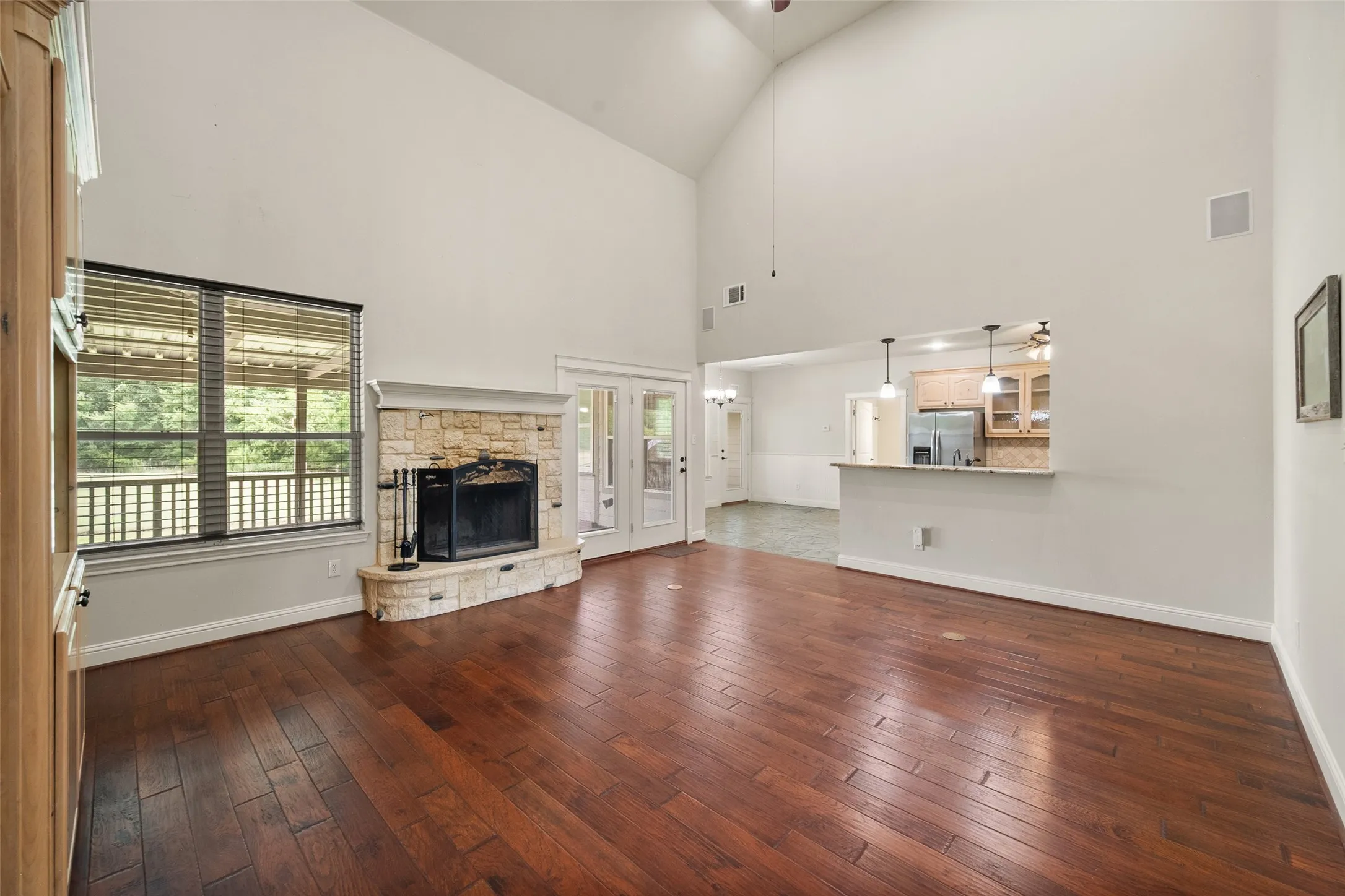 Vaulted living room with stone fireplace, expansive windows and an open connection to the kitchen and breakfast area.
