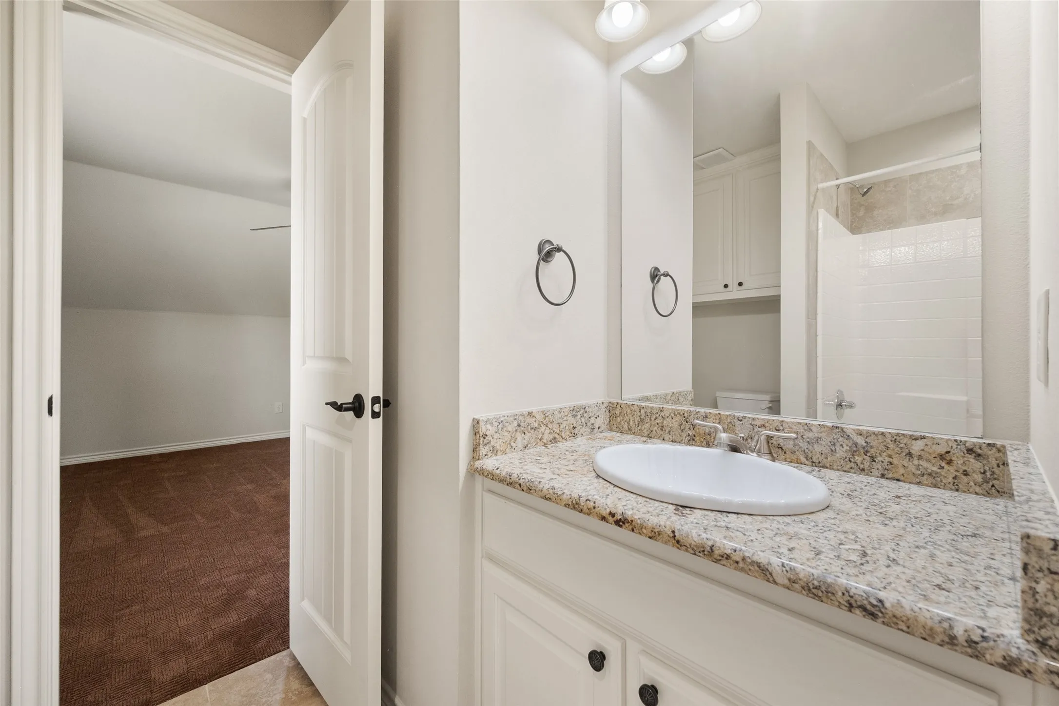 Jack-and-Jill bathroom with granite countertop, spacious vanity, tiled shower and convenient bedroom access.