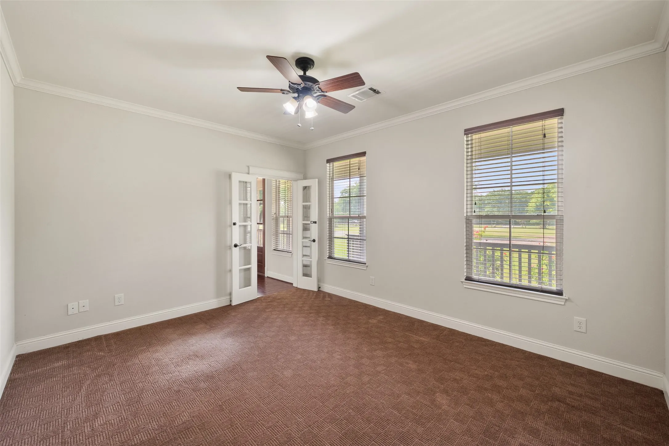 Flexible downstairs home office with abundant natural light, ceiling fan and room for a comfortable workspace.