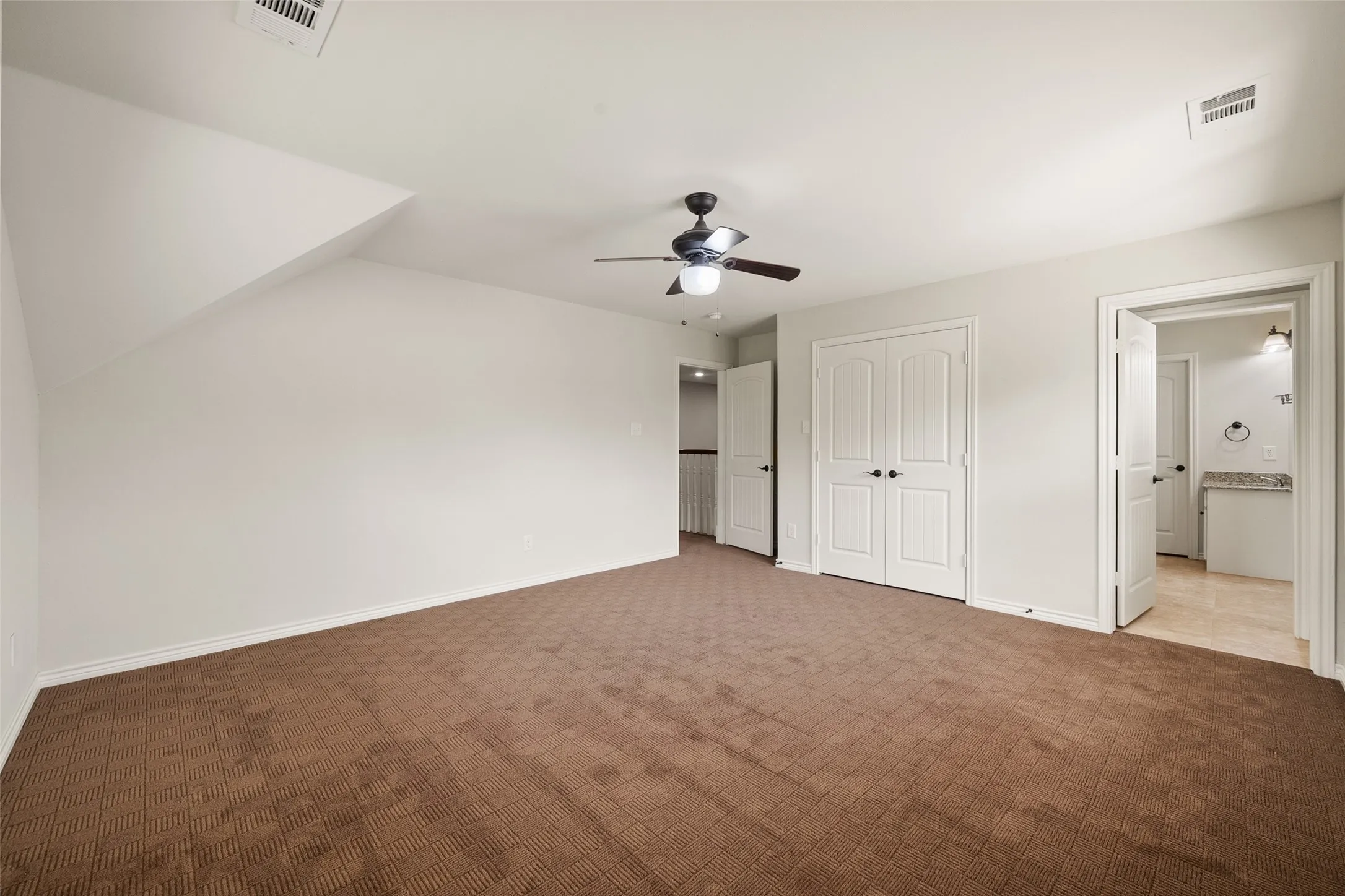 Versatile second primary upstairs bedroom with vaulted ceiling, ceiling fan, generous floor space and ensuite bathroom access.