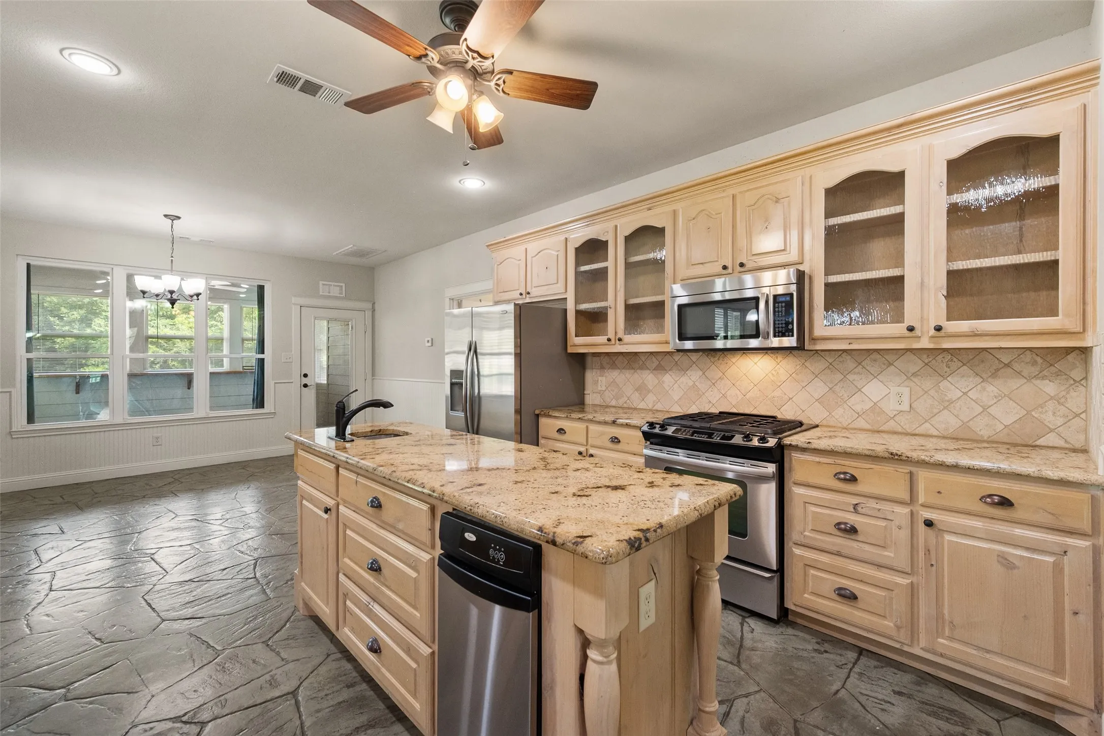 Well-equipped farmhouse kitchen featuring a gas range, built-in microwave, refrigerator and plentiful cabinet space.