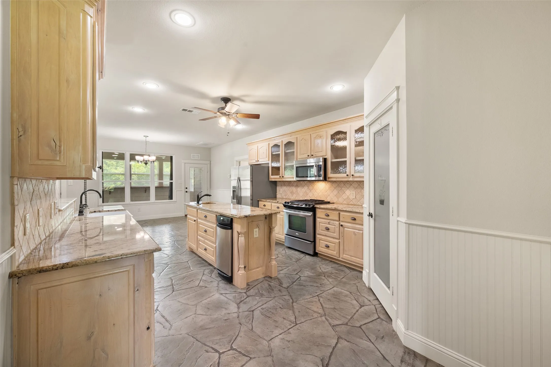 Spacious country kitchen with extensive wood cabinetry, granite countertops, gas cooking and durable tile flooring.