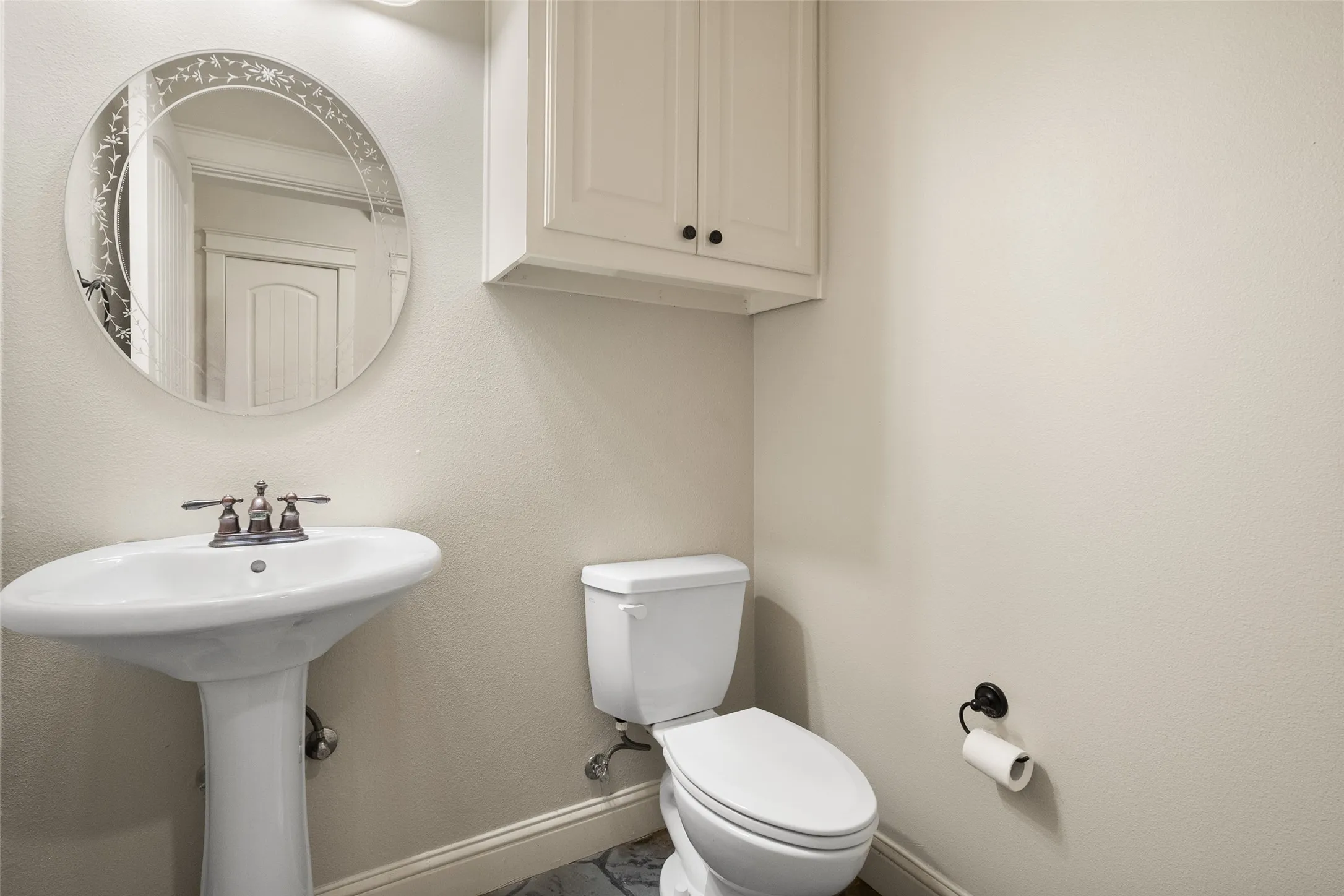 Convenient downstairs powder bathroom with pedestal sink, built-in storage and neutral finishes.