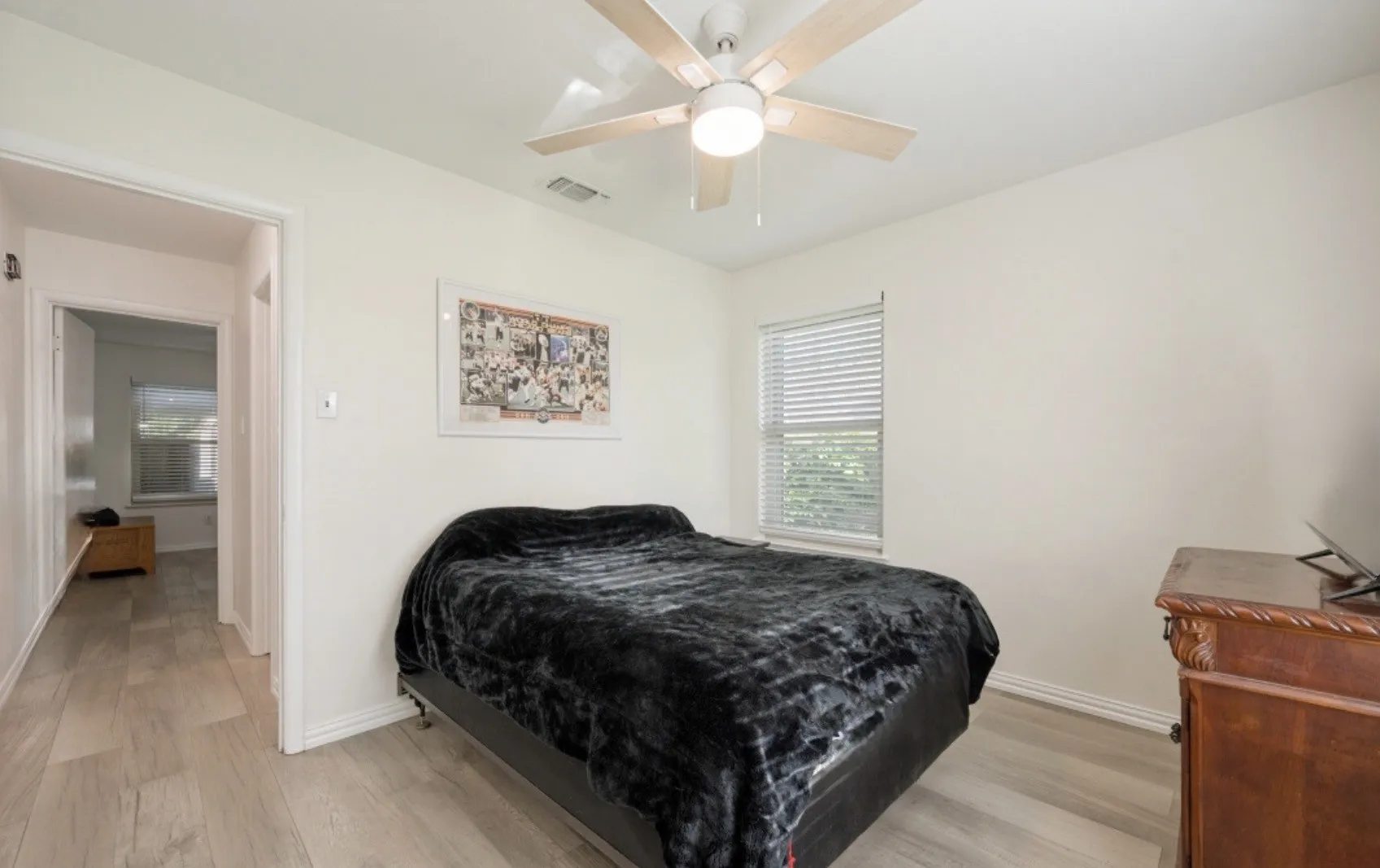 Bedroom featuring wood-finish flooring, a ceiling fan with light fixture, and a window with blinds