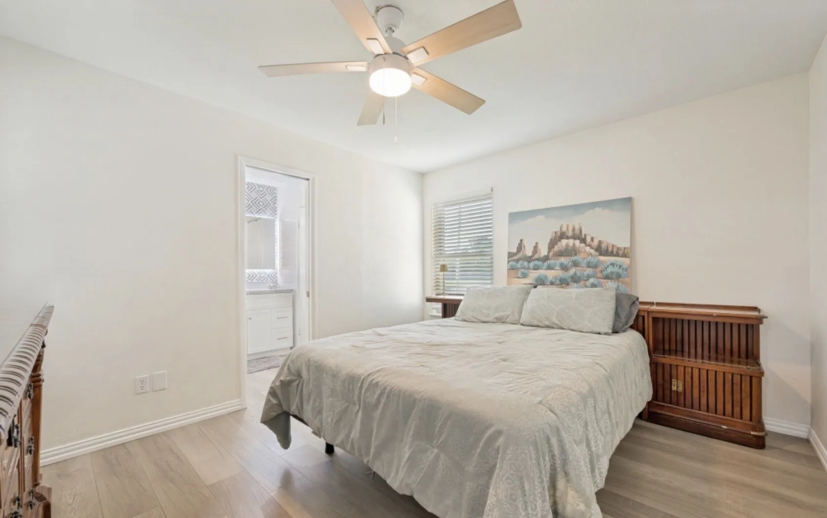 Bedroom featuring light wood-finish flooring, white baseboards, and a ceiling fan with light fixture