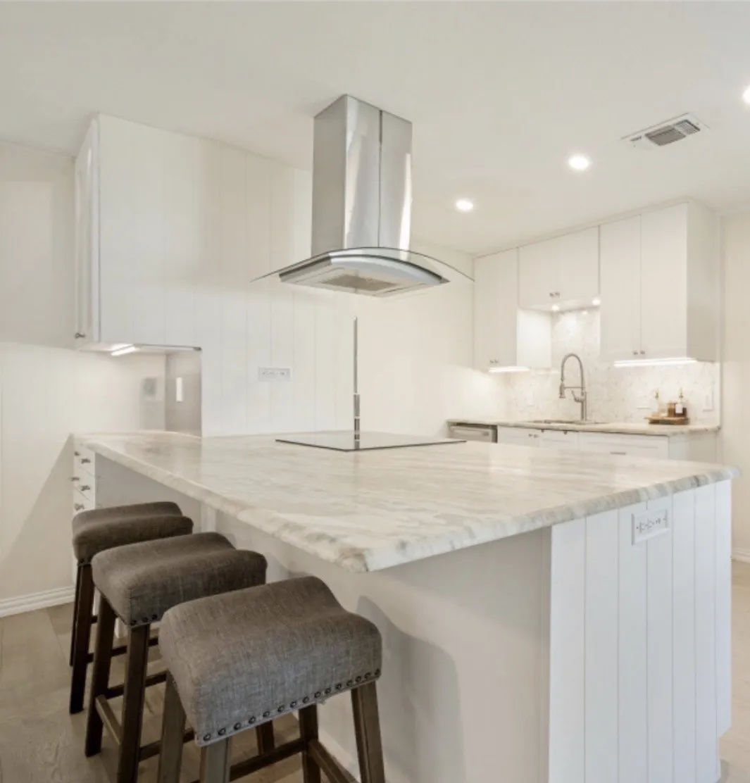 featuring a central island with quartz countertop, built-in cooktop, and an overhead stainless steel and glass range hood