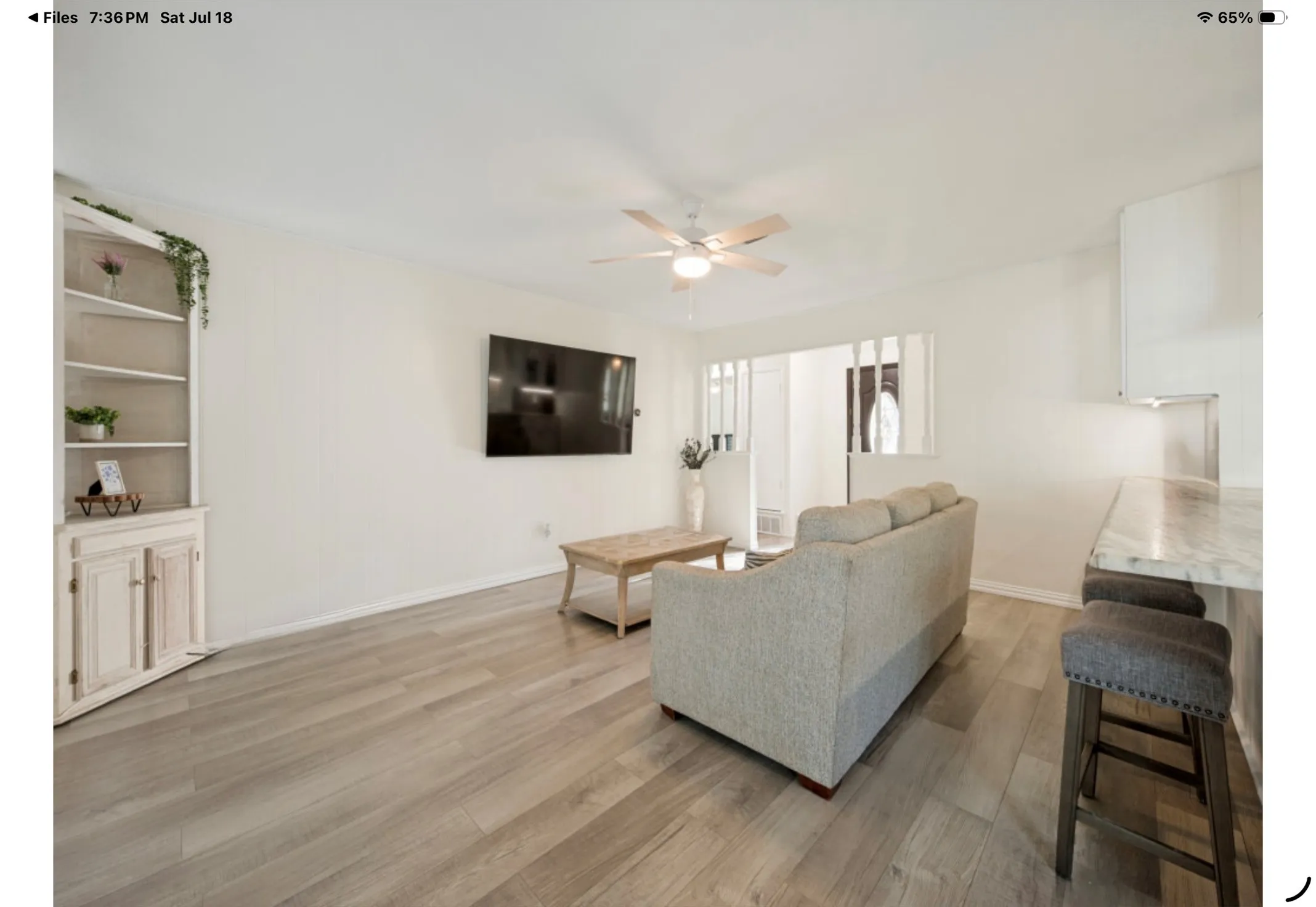 Open-concept living space featuring wood-finish flooring, a ceiling fan, and a built-in corner cabinet