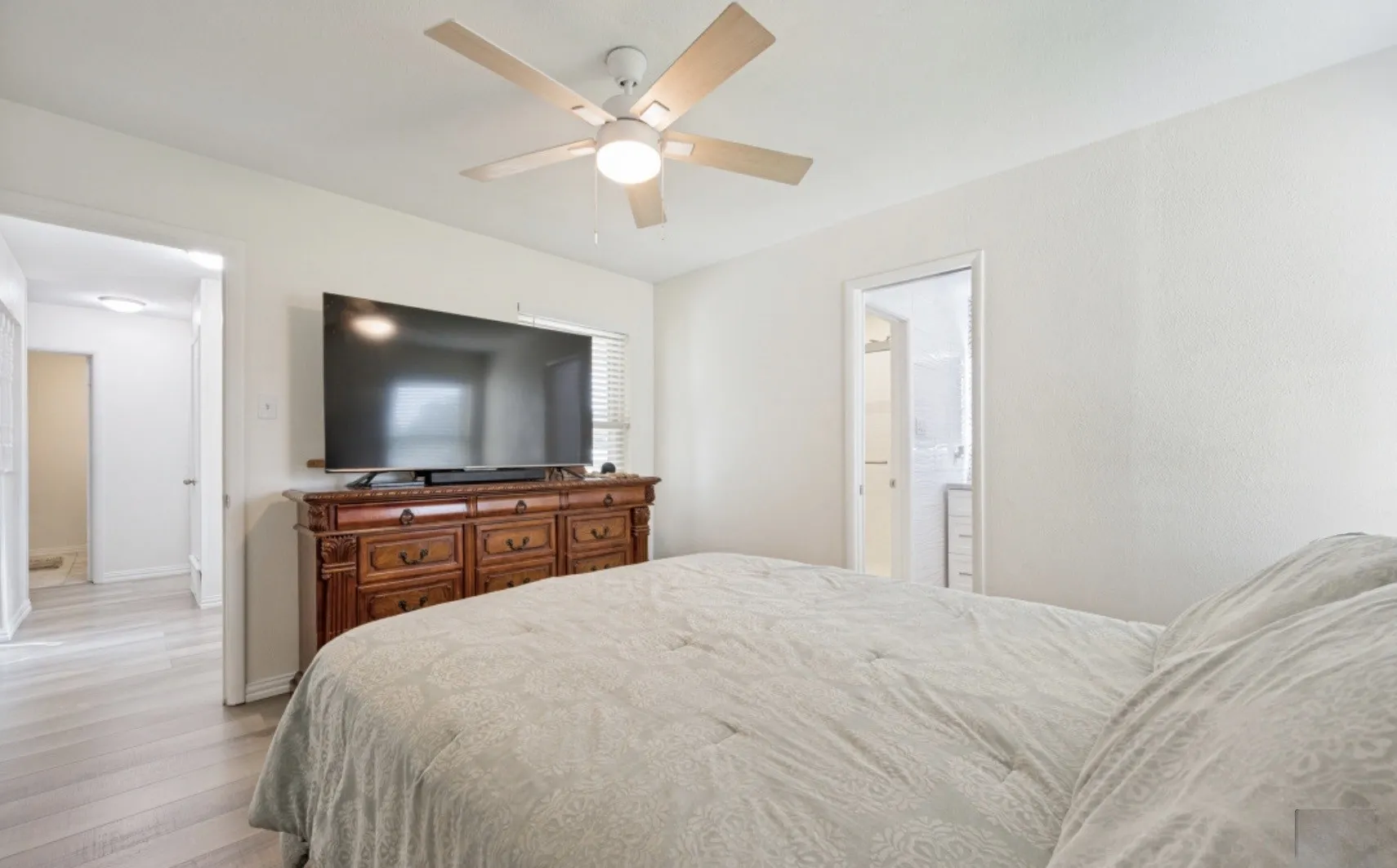 Bright room featuring light wood-finish flooring and a ceiling fan with integrated lighting