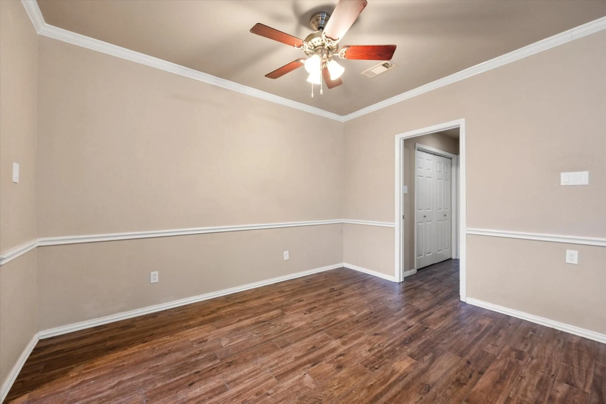 Dining area featuring wood-finish flooring, crown molding, chair rail molding, and a ceiling fan