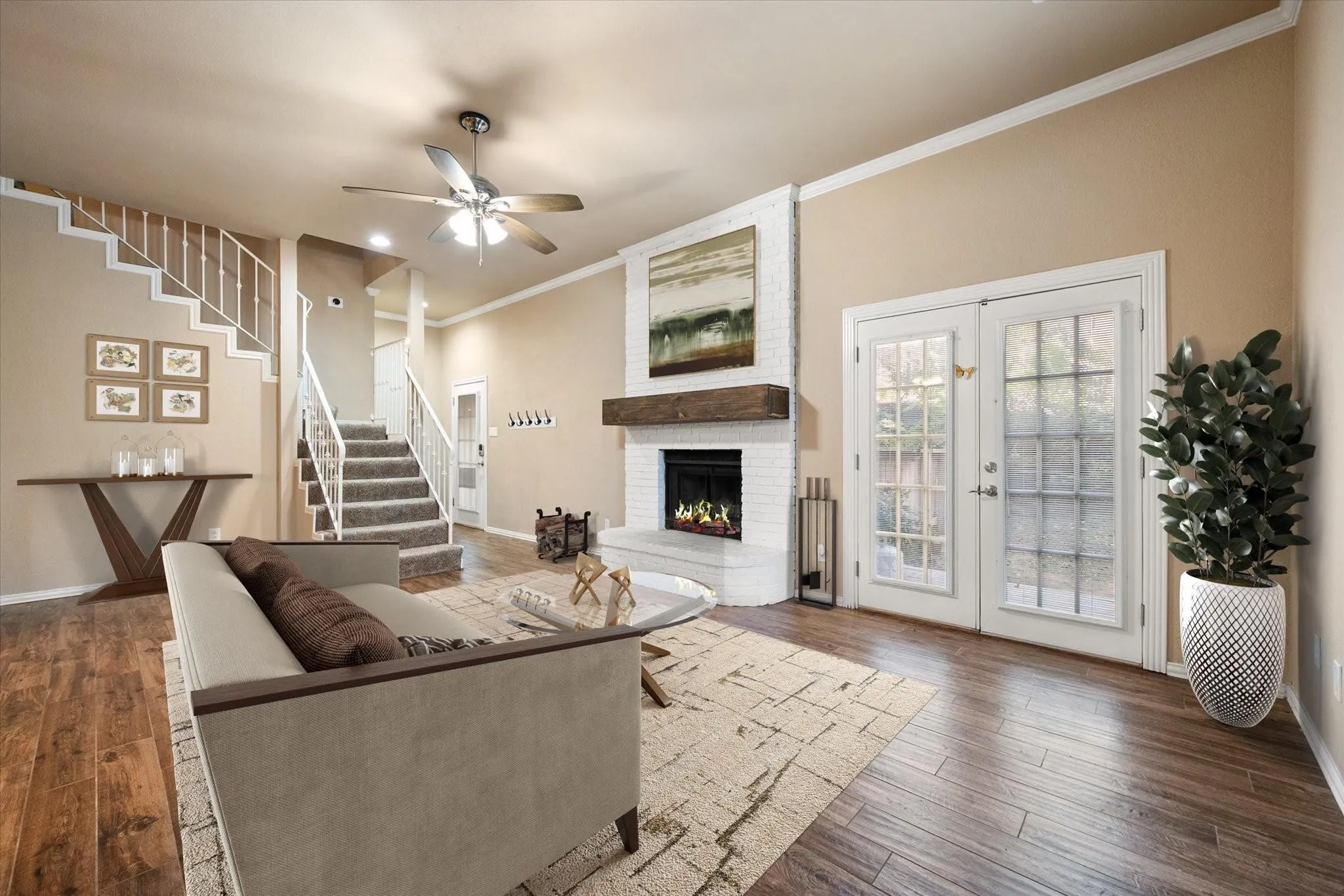 VIRTUALLY STAGED  Living area featuring wood-finish flooring, a white brick fireplace with a wood mantle, and a ceiling fan