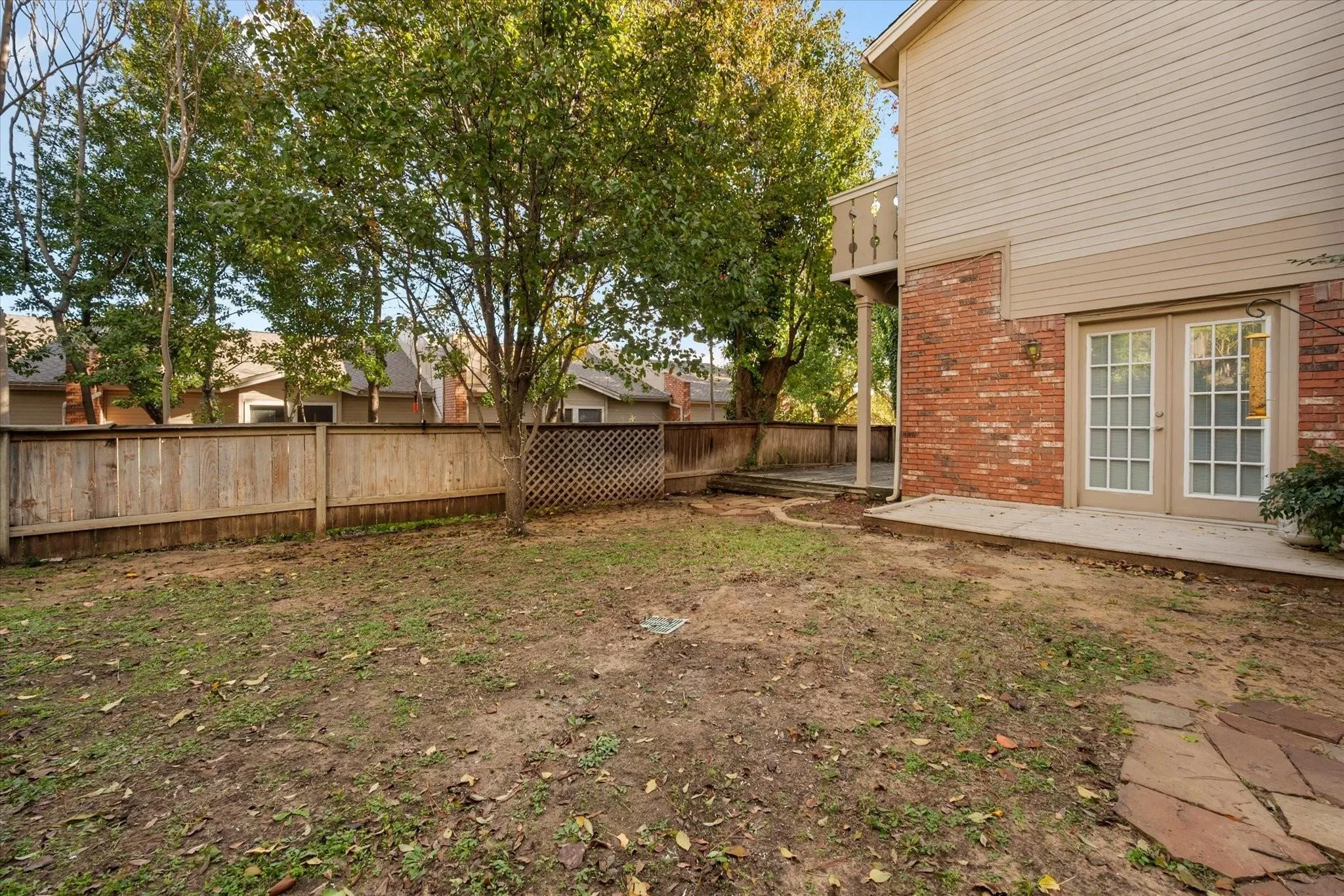Private backyard featuring mature trees, a wooden privacy fence, and a flagstone path