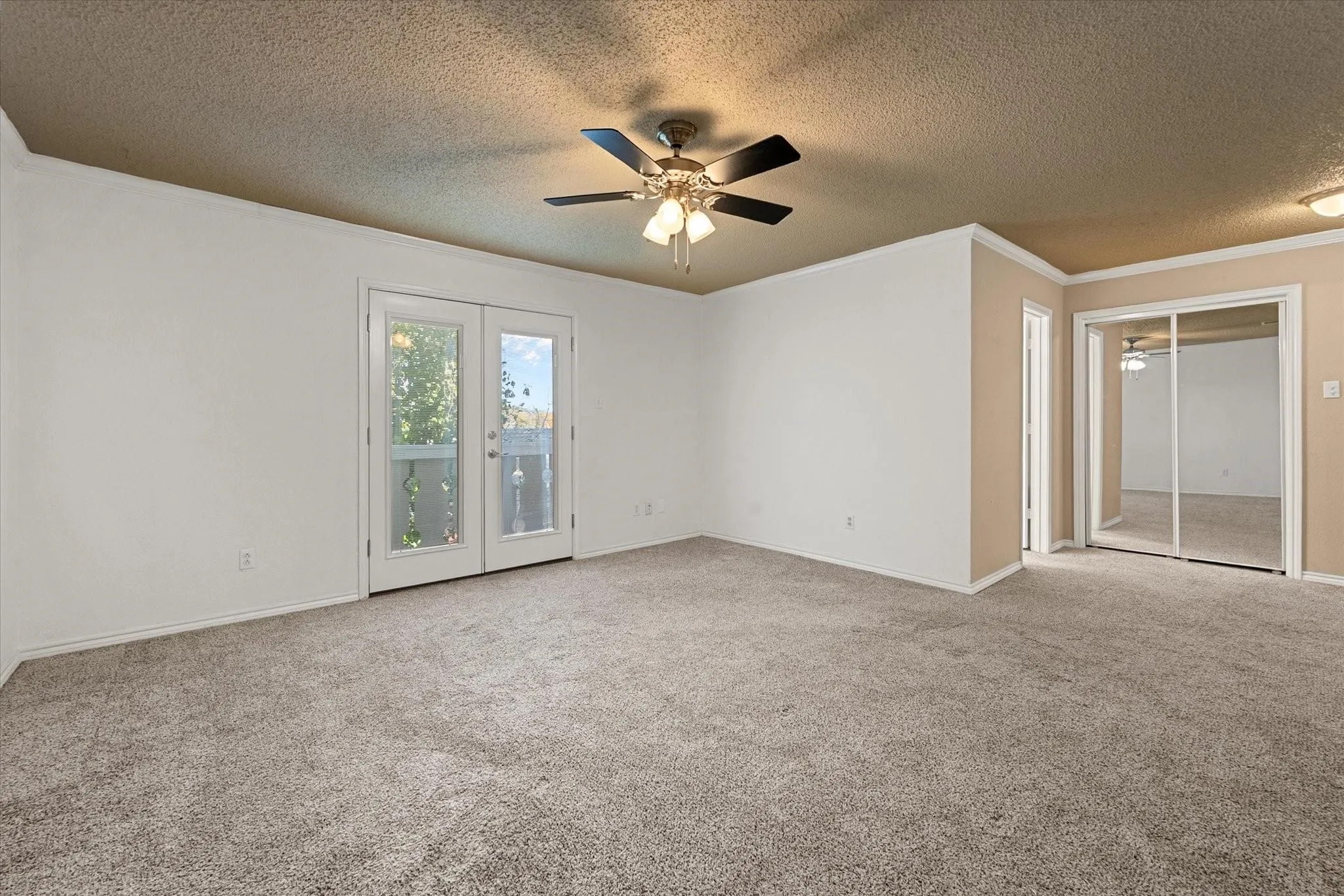 Spacious bedroom featuring neutral carpeting, a ceiling fan with integrated lighting, and white walls