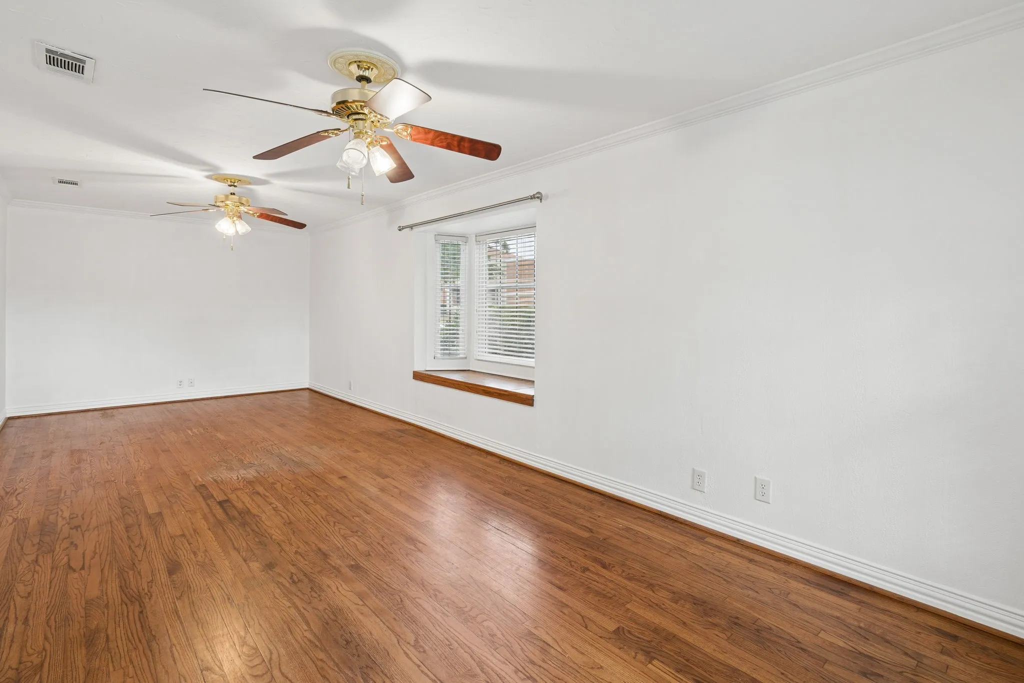Spacious interior featuring wood-finish flooring, white walls, and a bay window with a wood sill