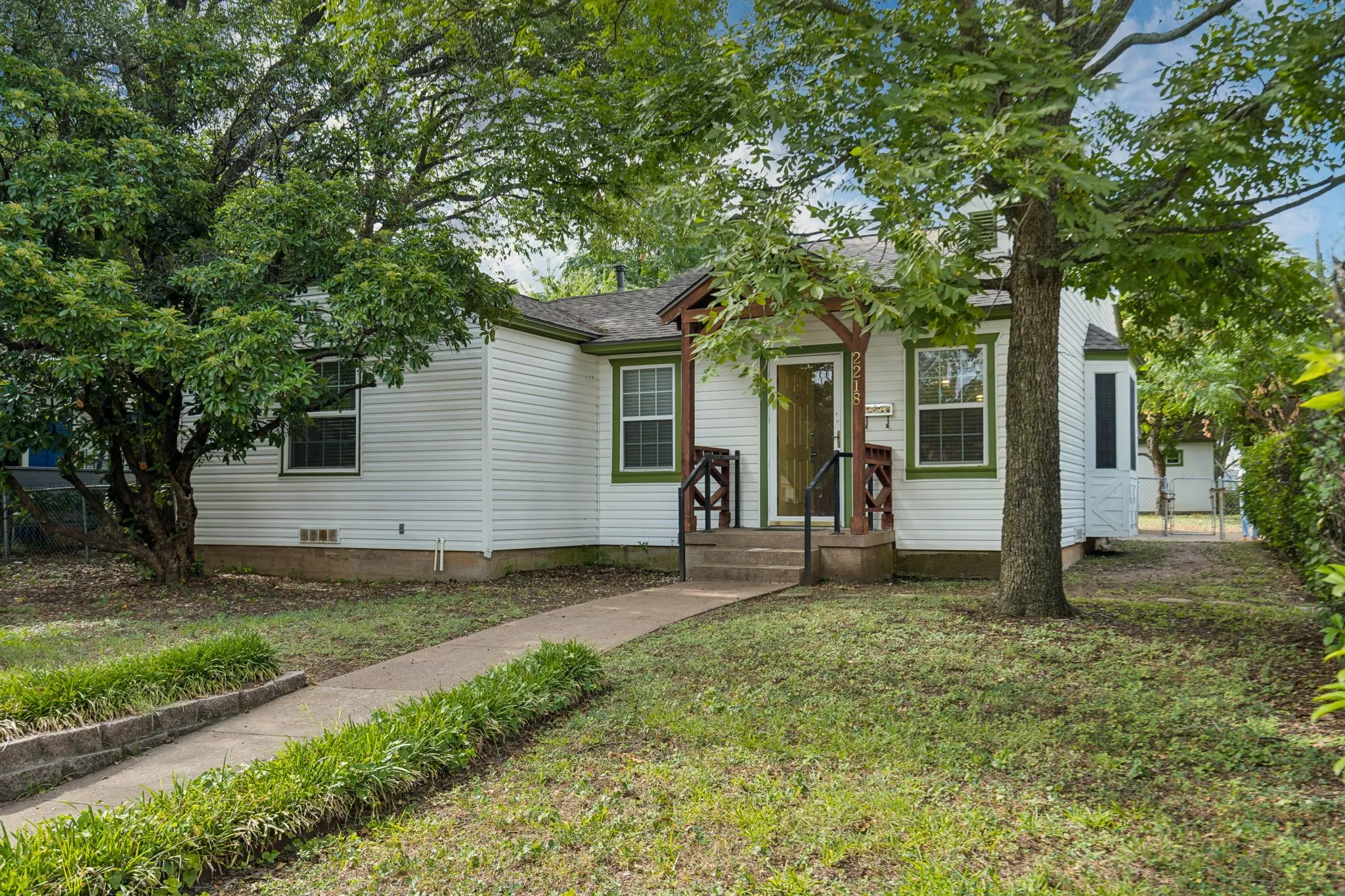 Single-story white siding residence featuring a covered front porch with dark wood accents and a concrete walkway