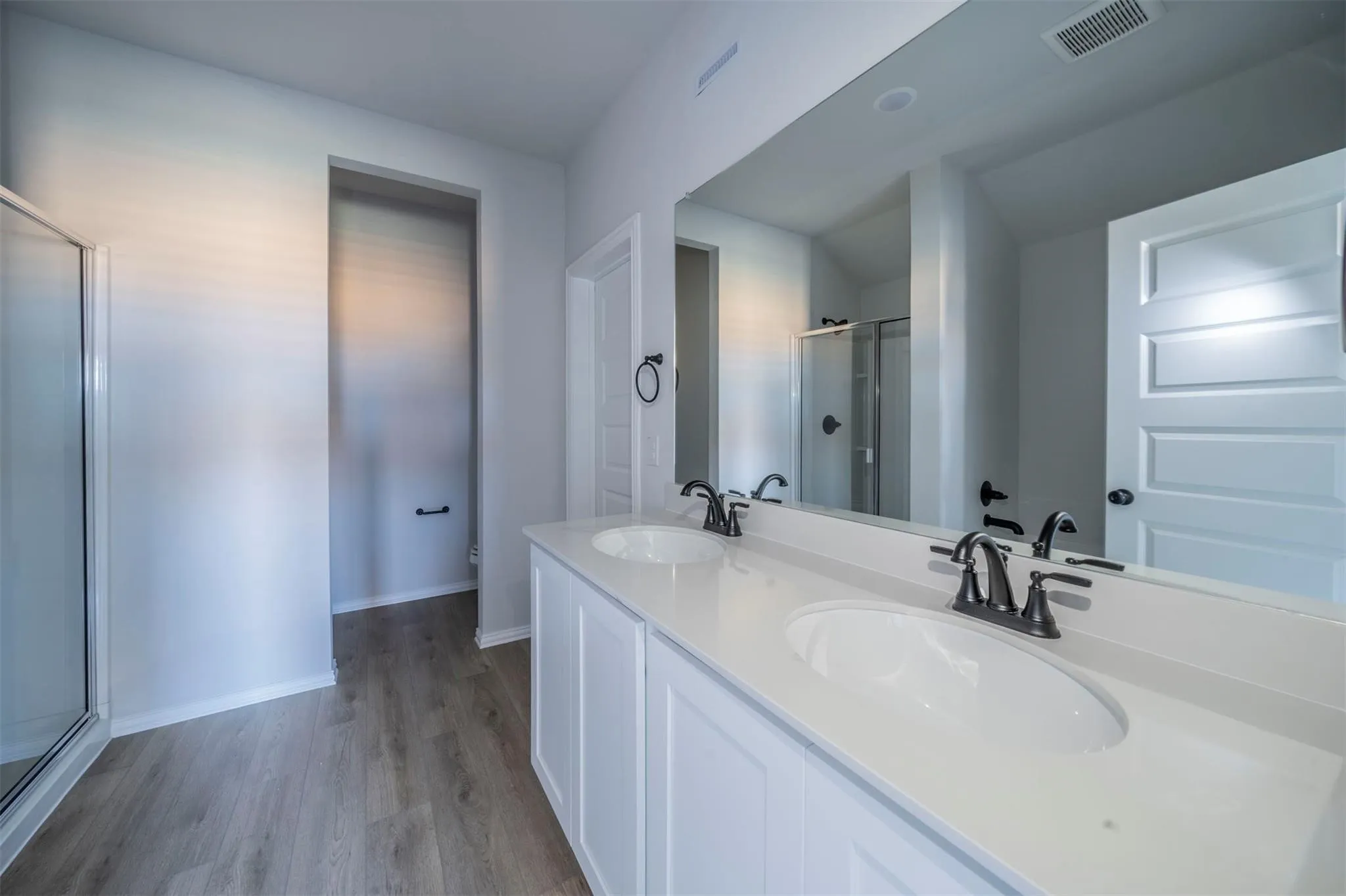 Dual vanity featuring white shaker cabinetry, white countertops, and dark bronze fixtures
