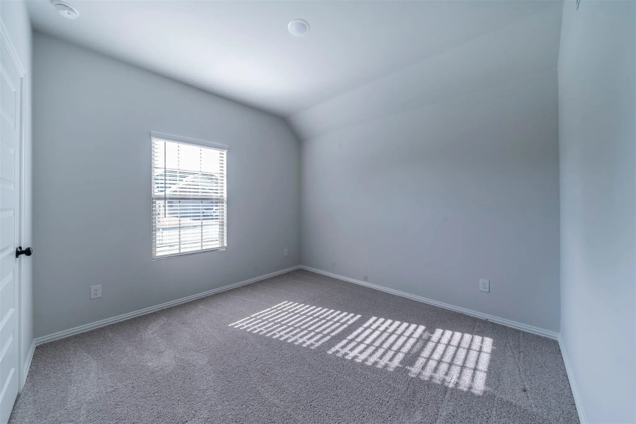 Room featuring a single window with horizontal blinds, sloped ceiling, recessed lighting, and grey carpeting
