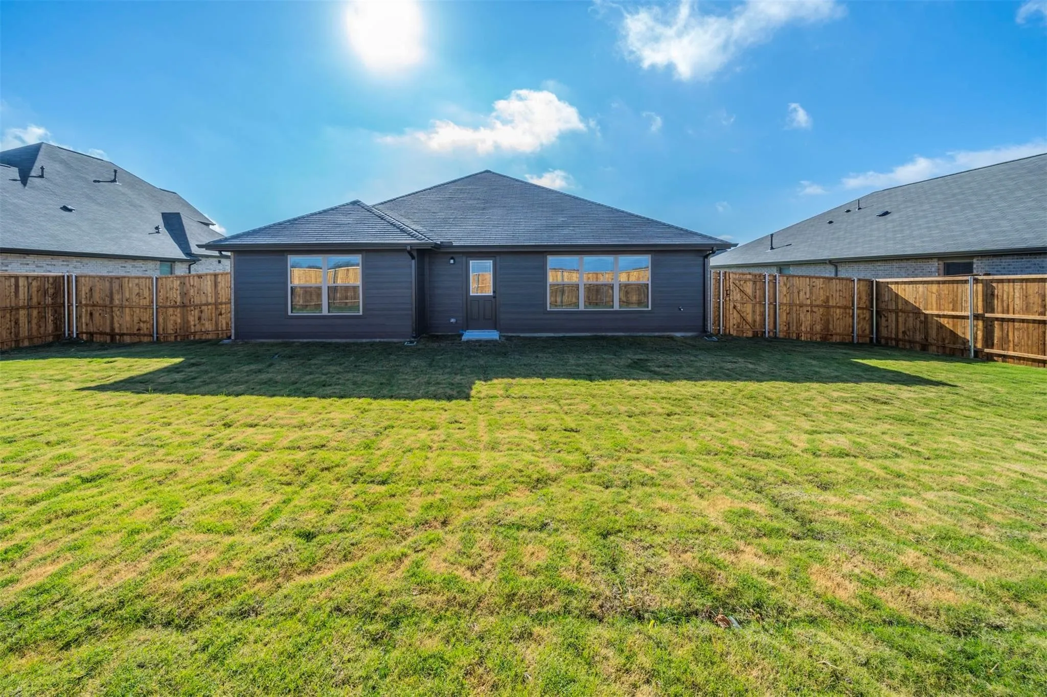 Expansive green lawn with a newly installed wood privacy fence enclosing the property